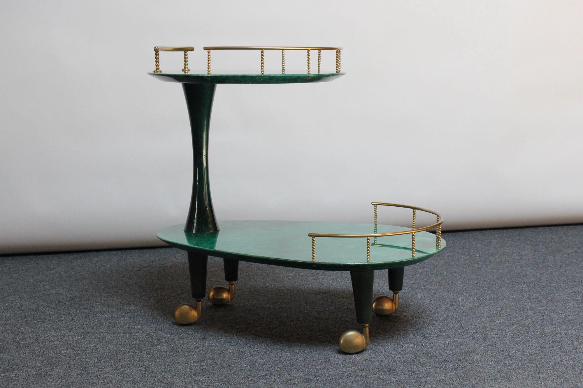Mid-Century Italian Modern bar cart / trolley designed in the 1950s by Aldo Tura.
Composed of two dyed malachite green goatskin surfaces connected by a sculptural pillar, all supported by brass caster wheels.
Uncommon, striking and desirable green
