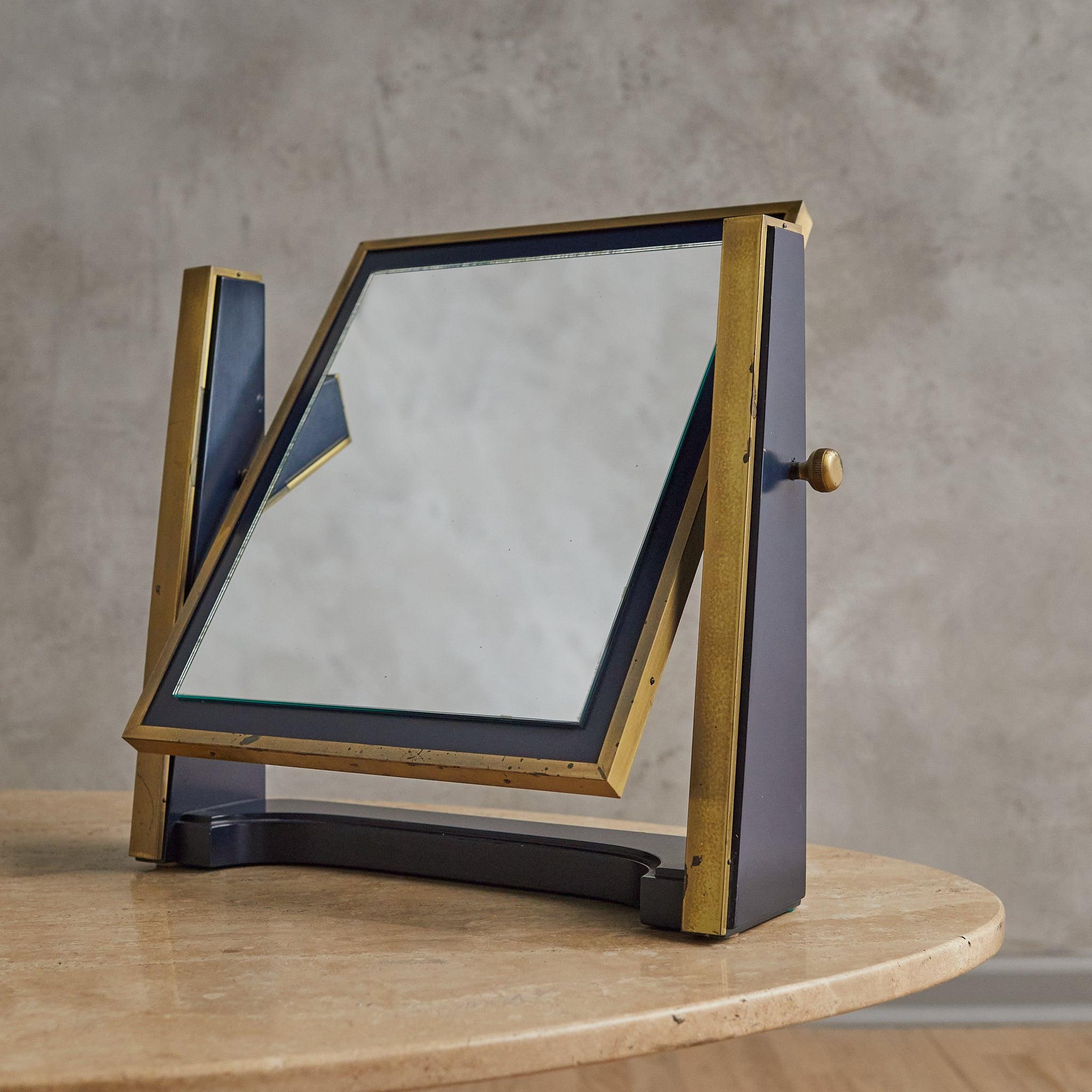Un élégant miroir de table italien des années 1960, parfait pour compléter une coiffeuse ou un bureau. Le cadre en bois laqué, d'un riche bleu d'encre, est rehaussé d'accents en laiton brossé. Son design moderniste est doté d'un cadre réglable,