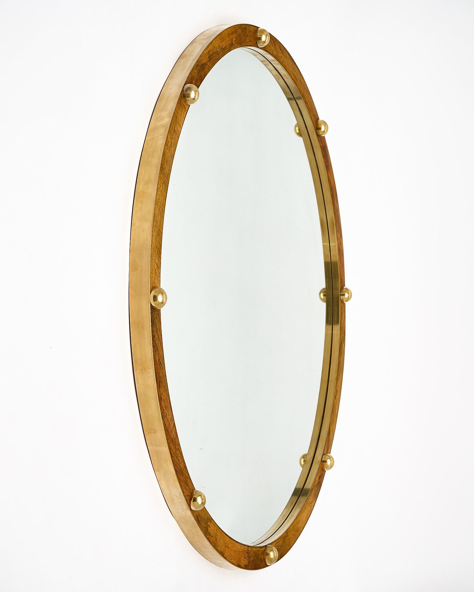Italian wooden and brass mirror. This round mirror features a wooden frame finished in French polish with half spheric solid brass studs.