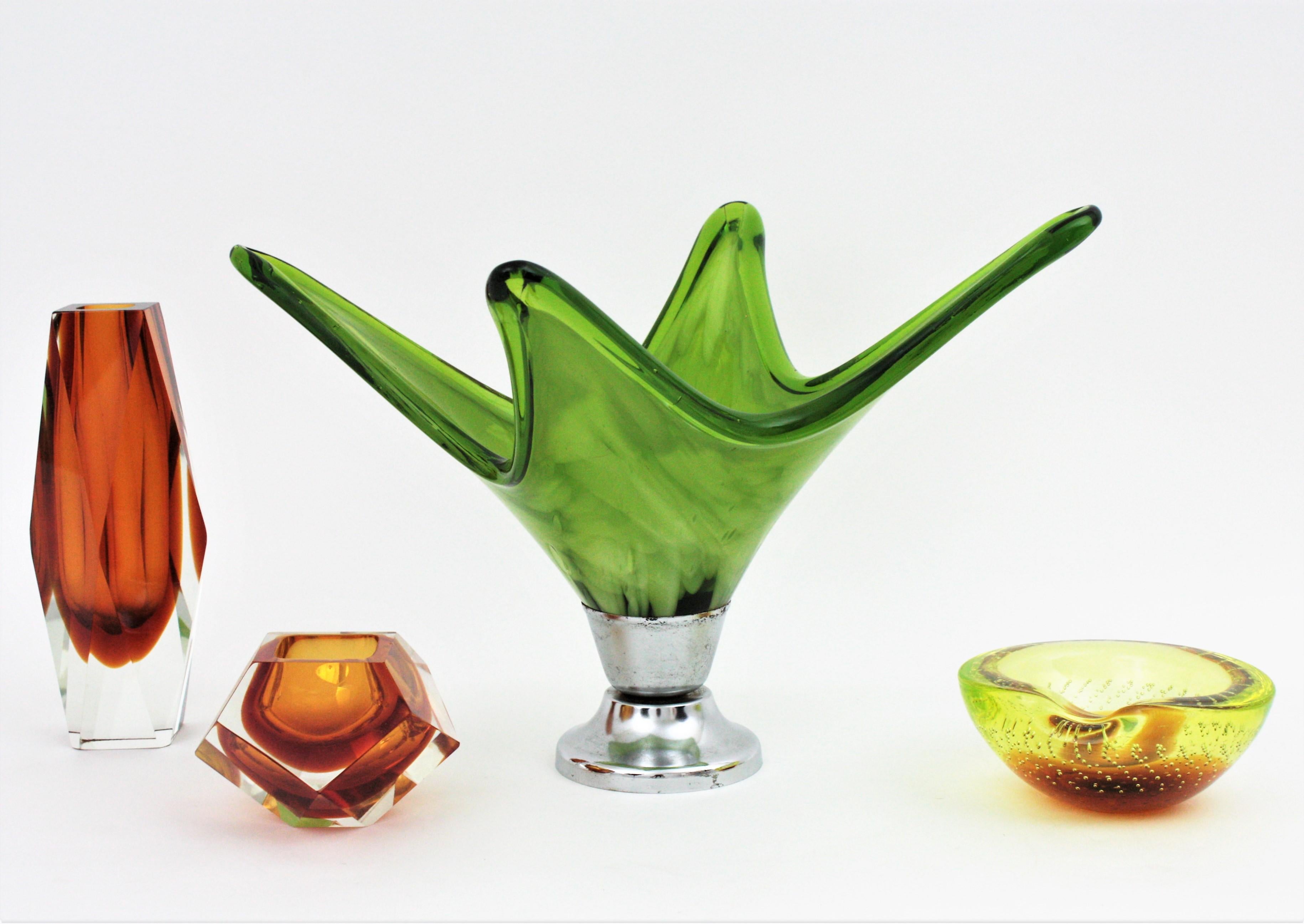 Vase centre de table en verre soufflé de Murano, vert et blanc, de style moderniste du milieu du siècle dernier. Italie, années 1960.
Cet élégant centre de table de Murano est réalisé en verre vert. 
Sa couleur attire le regard et son design sinueux