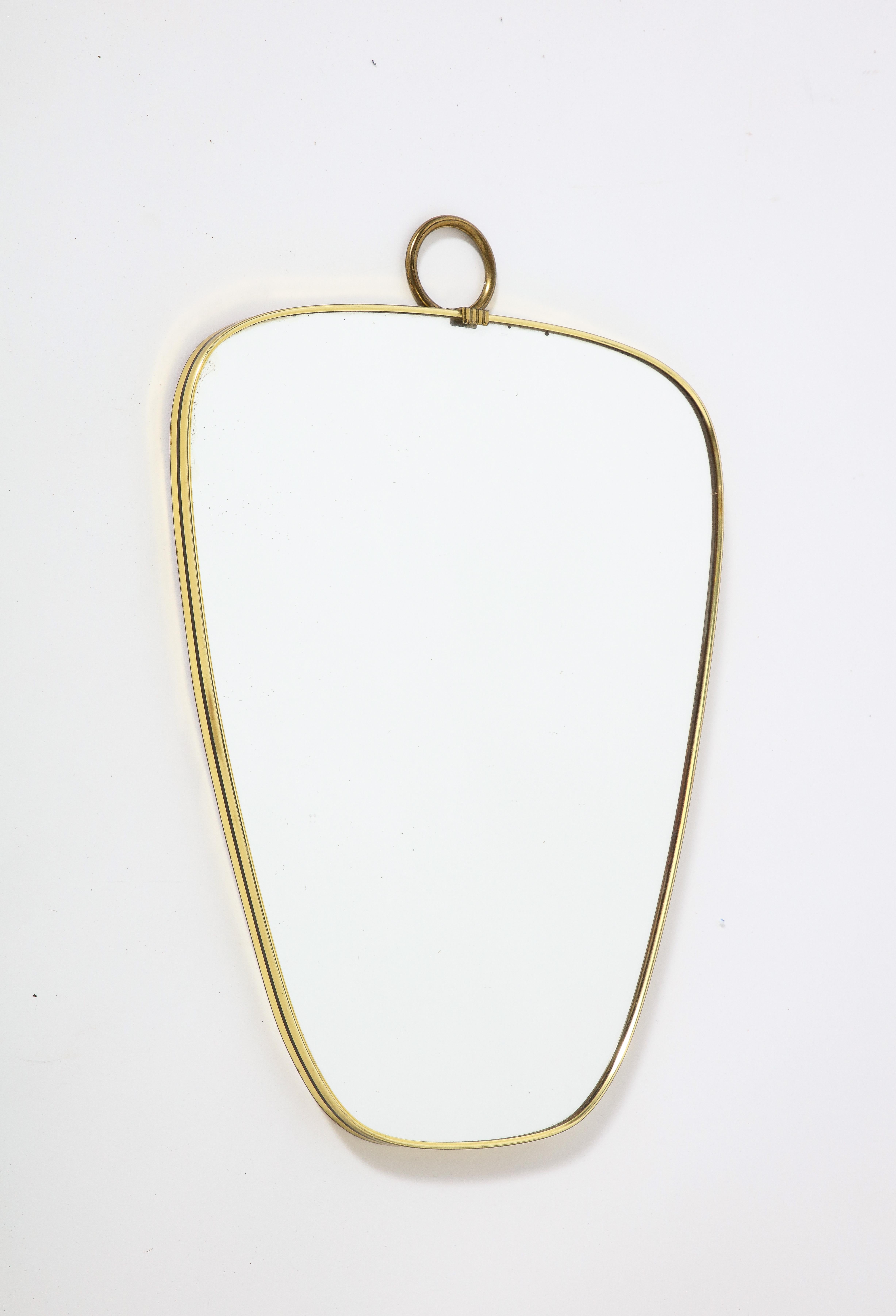 A charming Italian modernist brass shaped petite mirror with black metal stripe on the molding and ring with scallop motif at the crest.  
Italy, circa late 1960's / 1970
Size: 17 3/4