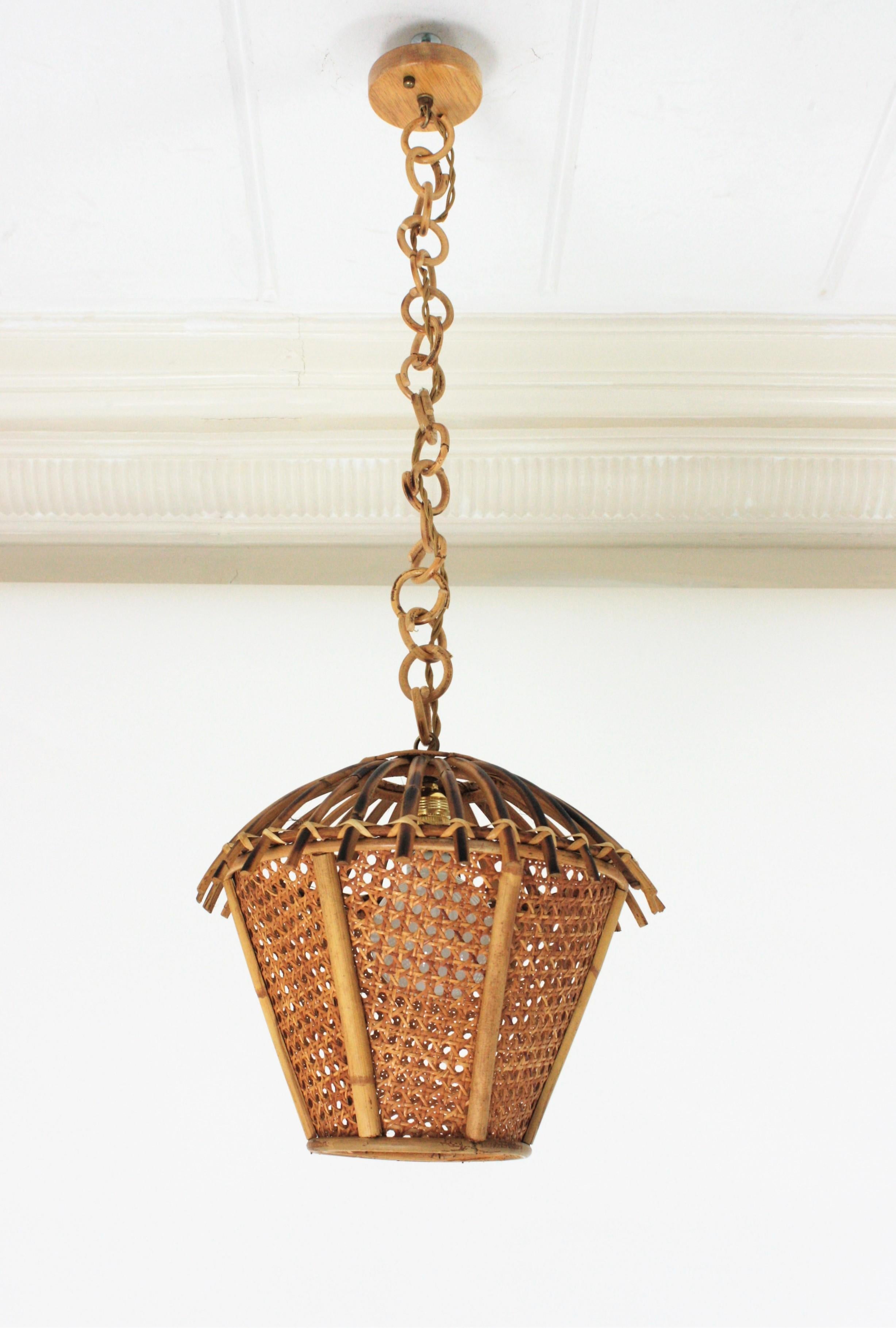 Mid-Century Modern woven wicker and rattan pagoda shaped lantern or pendant ceiling lamp. Italy, 1960s.
This pendant light features a woven wicker shade with rattan canes on the top. It has an eye-catching design as a pagoda combining Midcentury