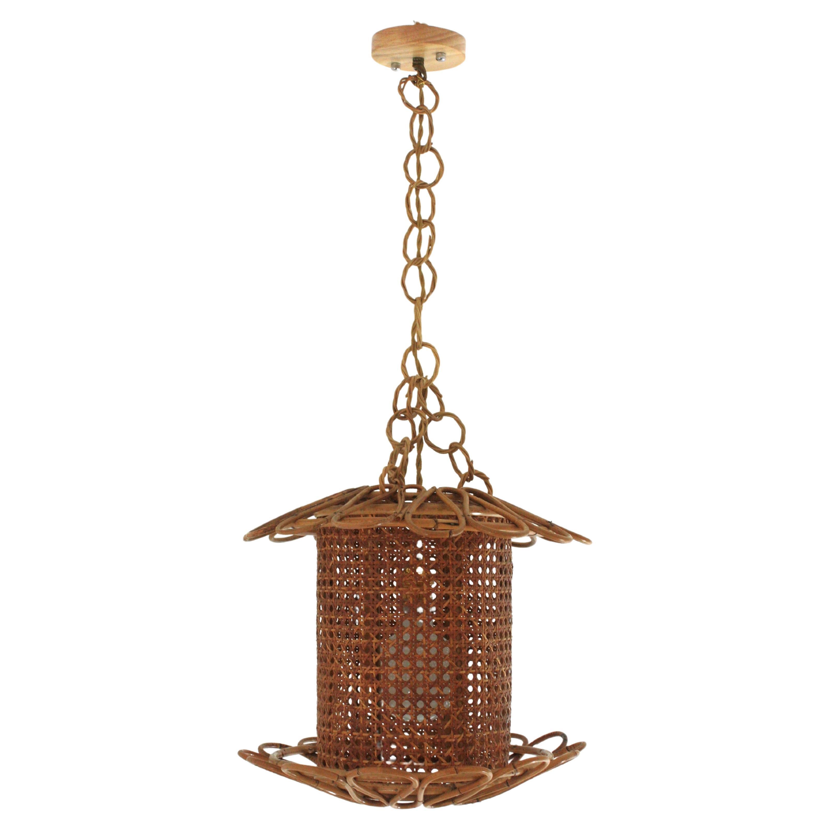 Mid-century Modern Rattan Woven Wicker Pendant Light
Beautiful Mid-Century Modern woven wicker wire and rattan pendant lamp / lantern, Italy, 1950s.
The woven wicker cylindrical shade of this lamp is accented by handcrafted rattan details as petals
