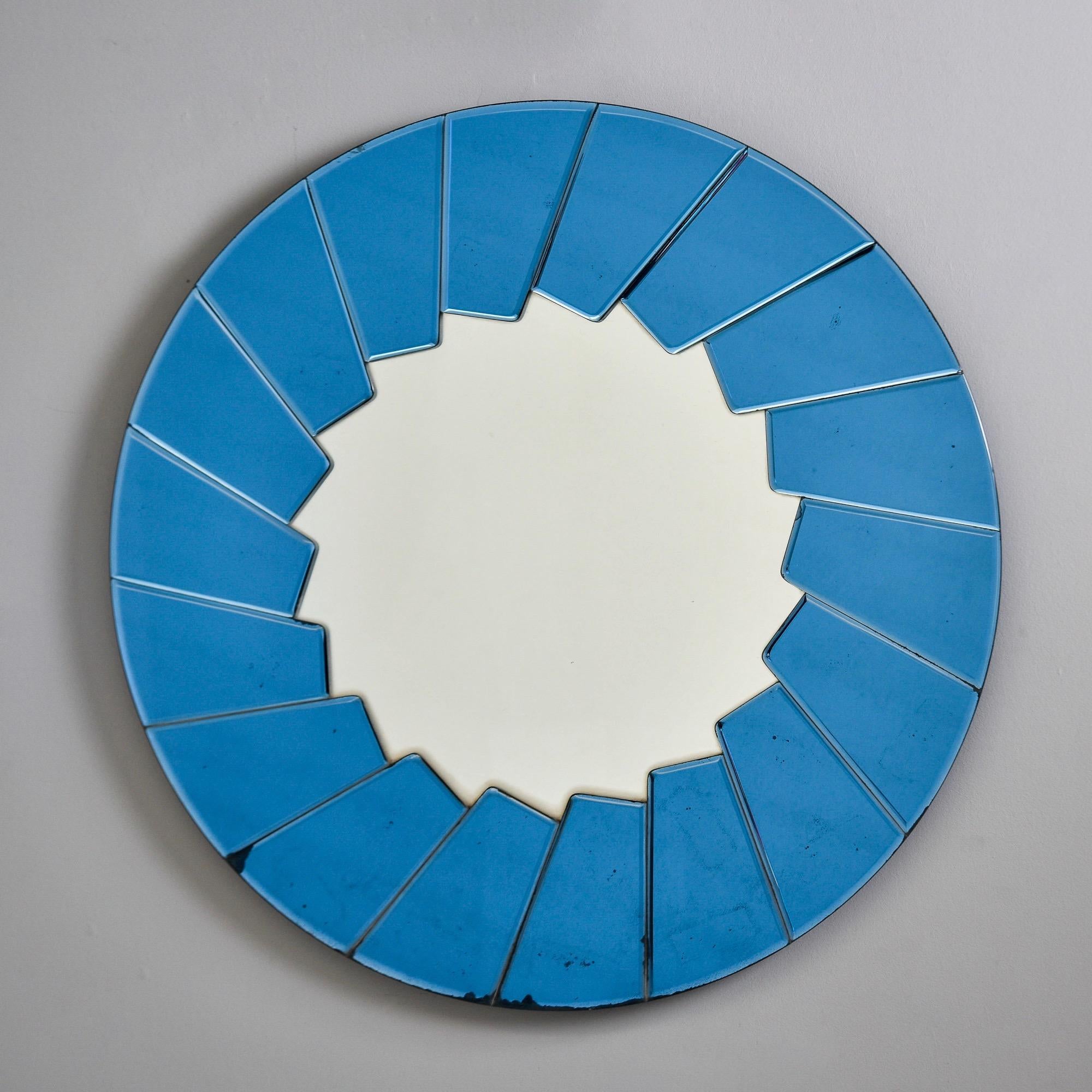 Found in Italy, this round mirror dates from the 1960s. Center mirror is framed by applied blue colored glass elements. Back has a metal hanger. Unknown maker. Very good overall vintage condition with some scattered dark spots to blue colored glass