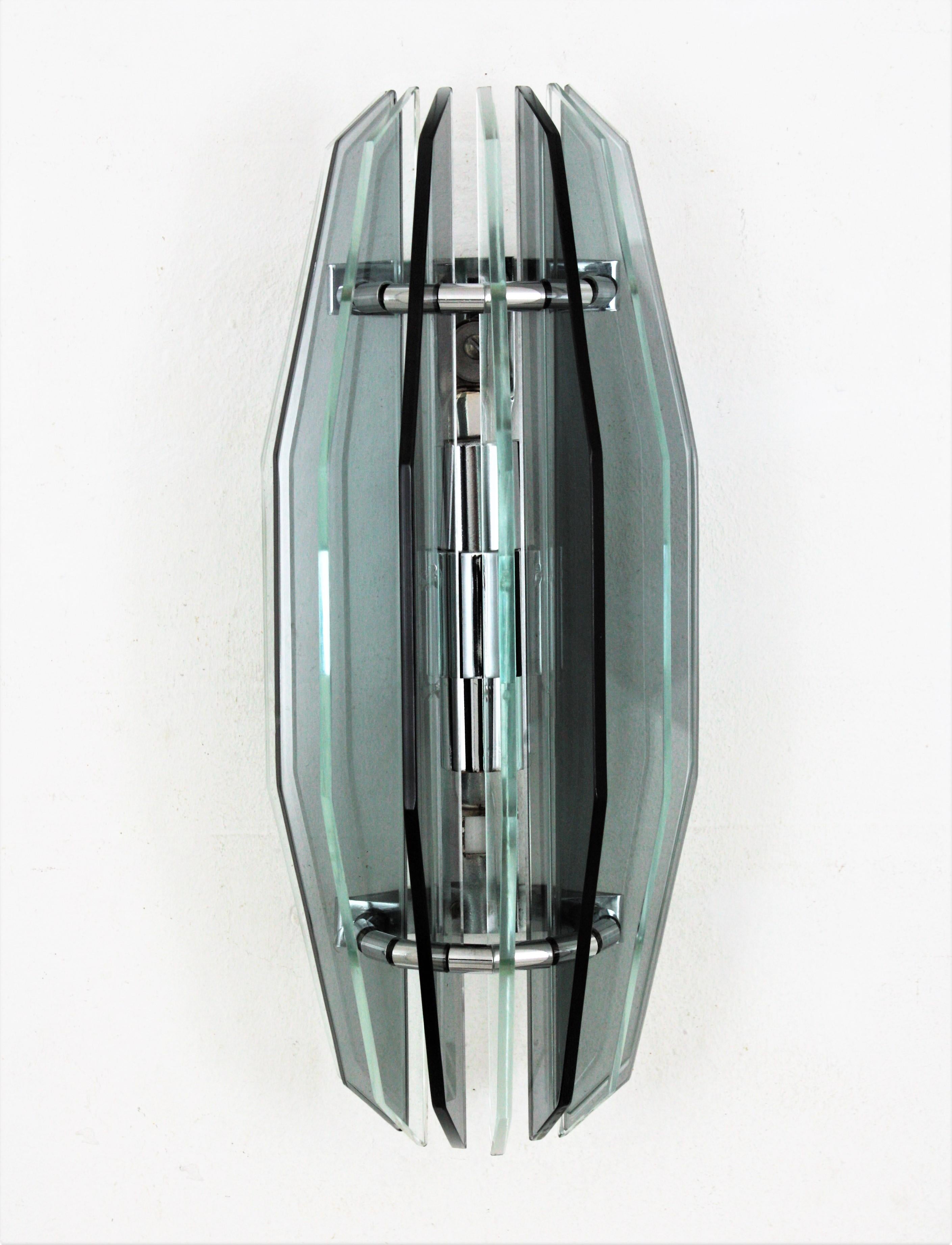 Large smoke grey and clear glass wall light in the style of Fontana Arte. Italy, 1960s.
Alternating clear and gray glasses separated between them by small steel cylinders and attached to a chromed steel base.
Two lights with E27 bulb holders. Newly