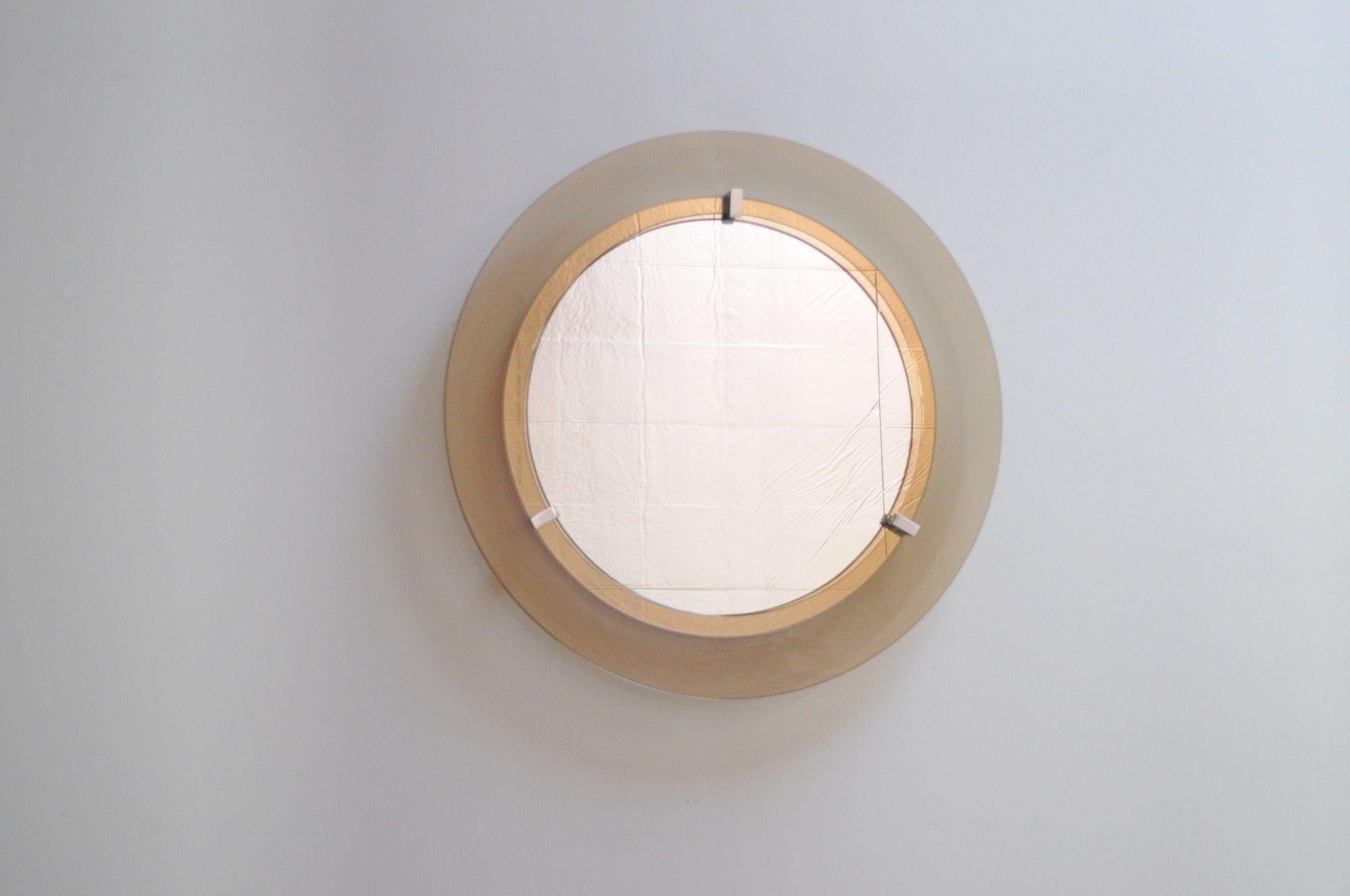Veca wall mirror composed of deeply inset mirrored glass attached to an enameled metal base and mounted via three chrome brackets to a circular smoked-glass frame (ca. 1960s, Italy).
Very good, vintage condition with only light white enamel loss to