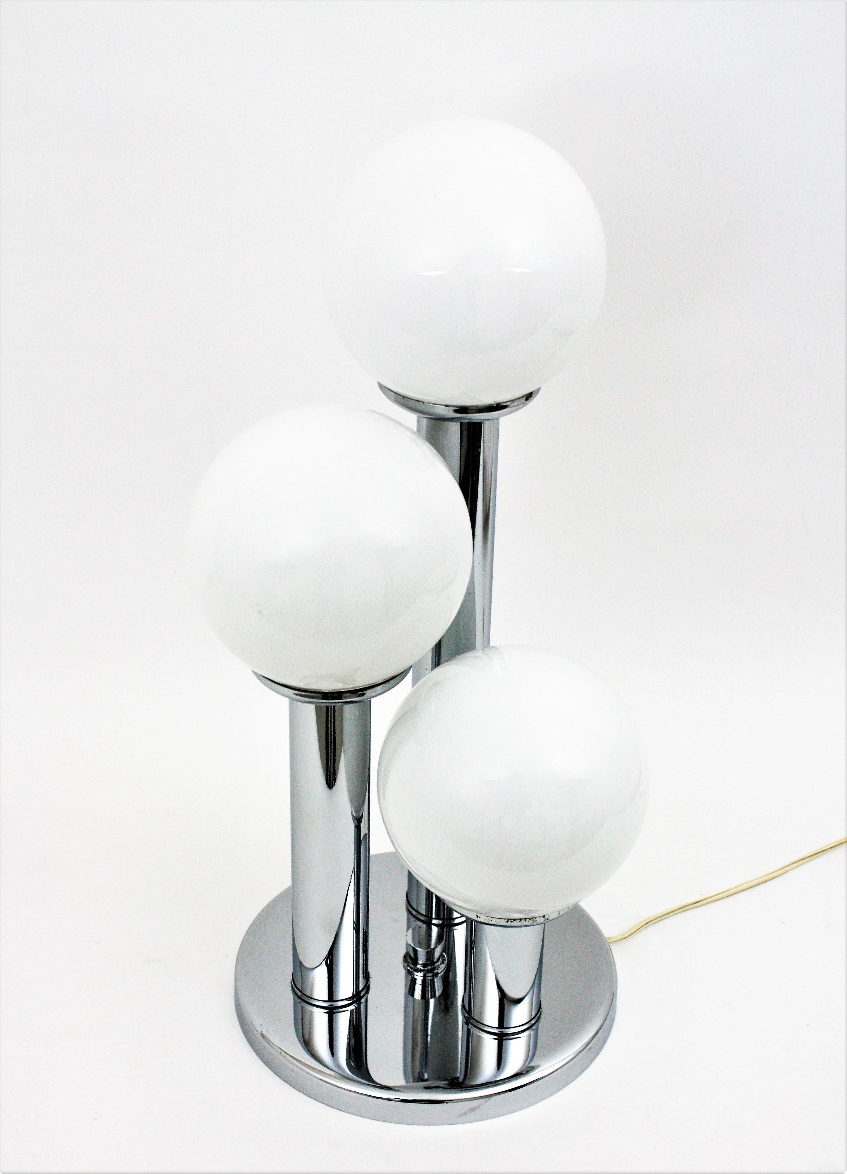 A beautiful table lamp with three chrome columns in different heights holding opaline glass globes. Italy, 1960s
It has three chromed steel columns holding 3 glass globe light in different heights and standing up on a round base.
Beautifully