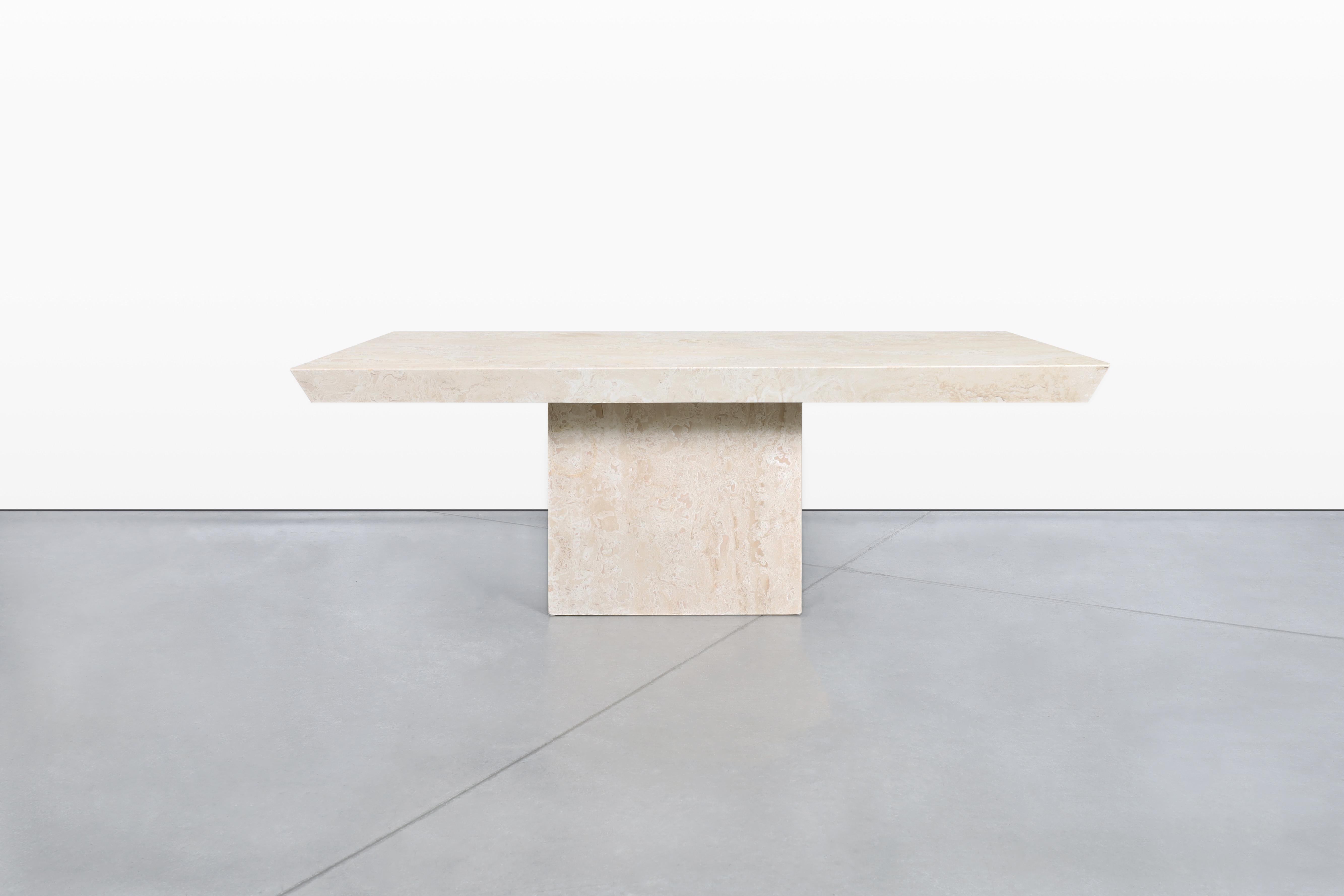 Cette exquise table de salle à manger en travertin italien, conçue en Italie dans les années 1980, met en valeur la beauté intemporelle de la pierre naturelle. La surface de la table présente un grain étonnant qui met en valeur les variations et les