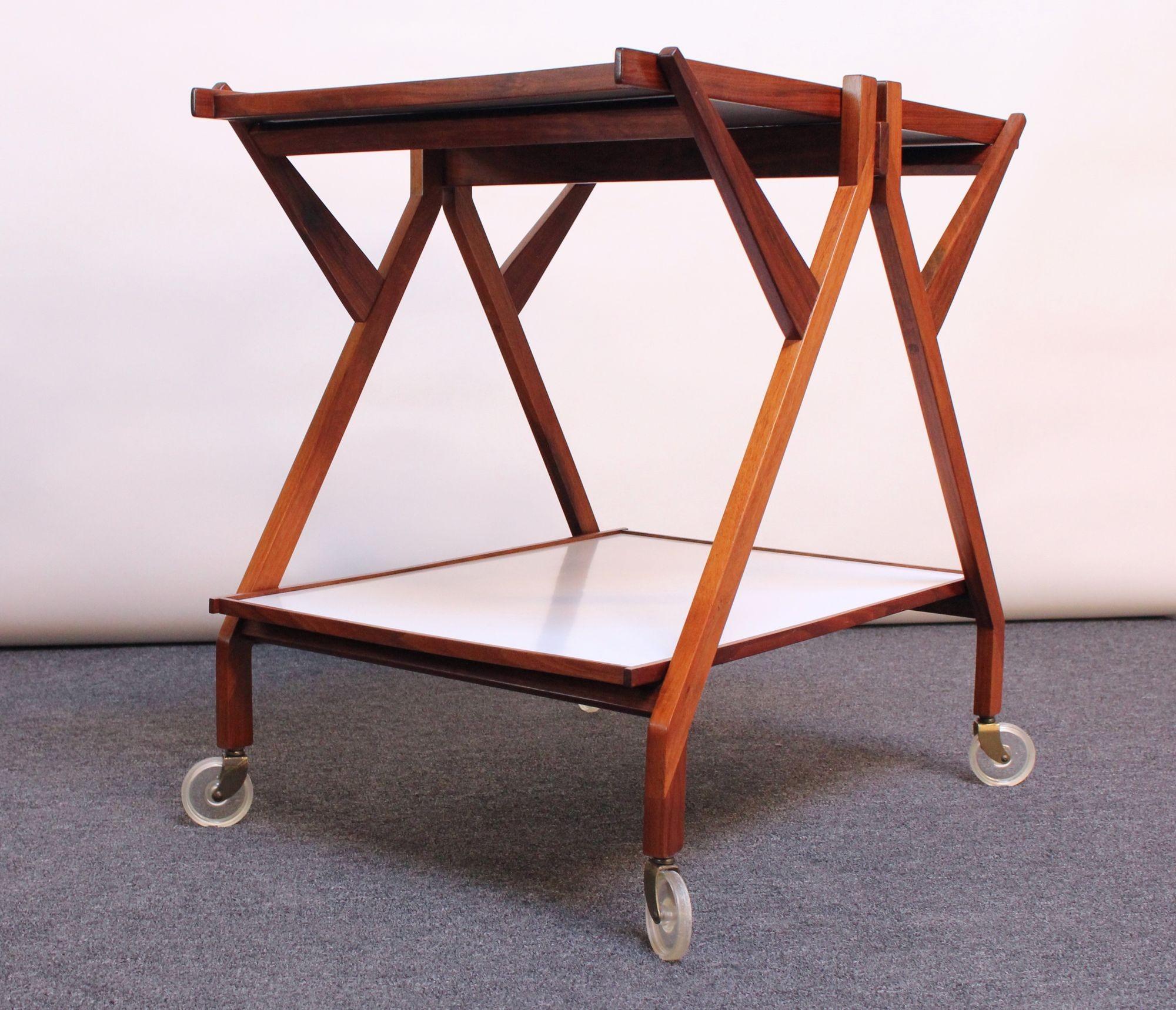 Sculptural Modernist walnut bar cart/trolley with two laminate surfaces, all supported by caster wheels (ca. 1960s, Italy). Sharp, crisp lines and superior craftsmanship utilizing complex wood joinery techniques, though designer is unknown. 
Top