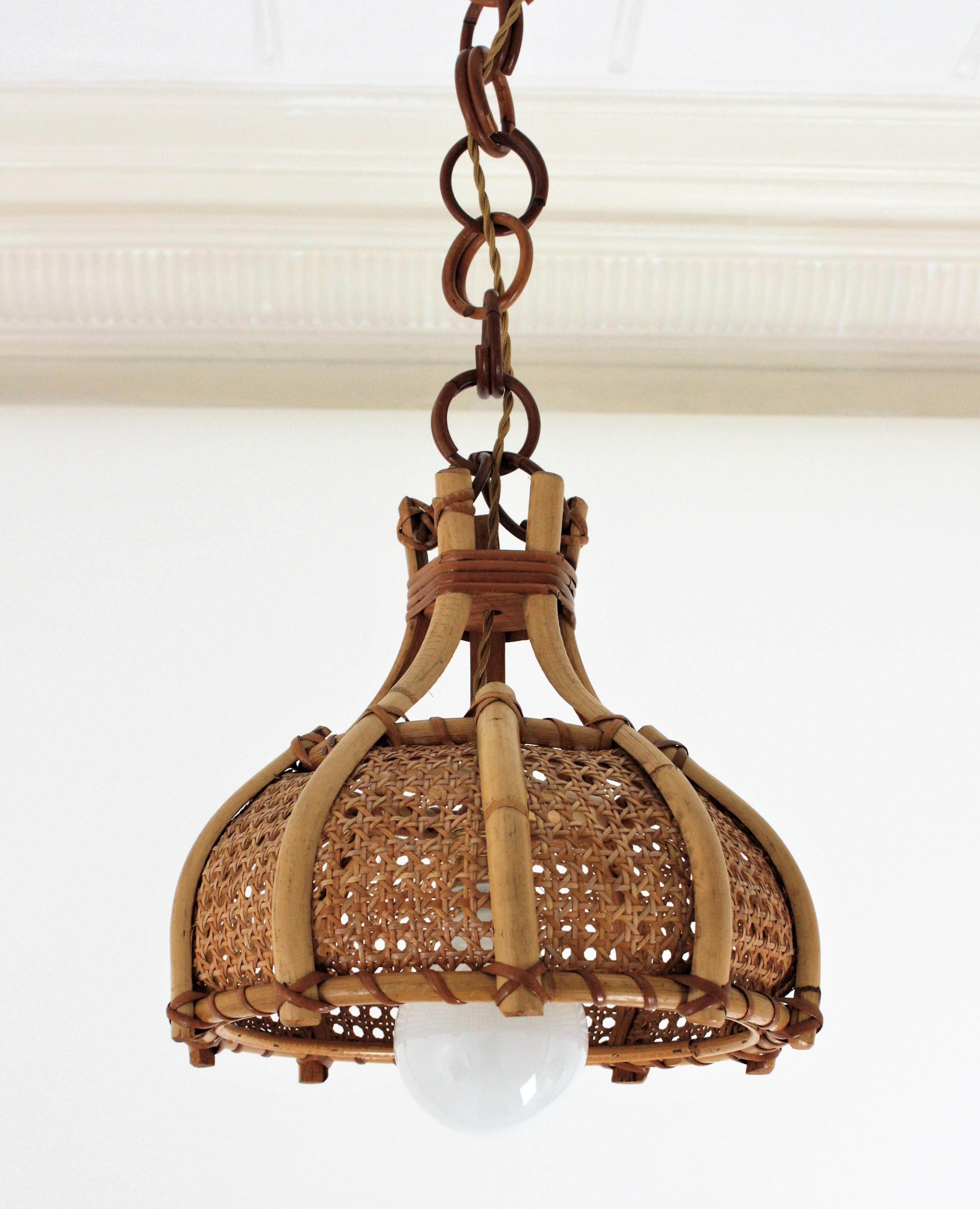 Mid-Century Modern rattan, woven wicker wire and bamboo bell pendant / hanging light, Italy, 1960s.
This beautiful suspension lamp features a bamboo and wicker wire bell shaped shade with bamboo decorative vertical bars. The shade is accented by
