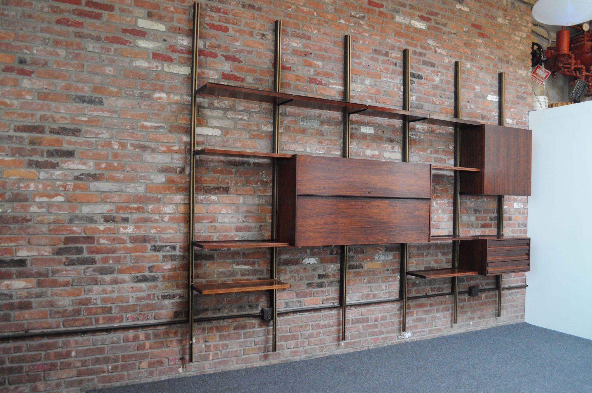 Large modular rosewood bookcase/wall unit by Osvaldo Borsani for Tecno (ca. 1960, Italy).
Composed of six gold aluminum uprights forming five bays/sections.
Includes:
-locking bar unit with a removable (non-adjustable) shelf and glass