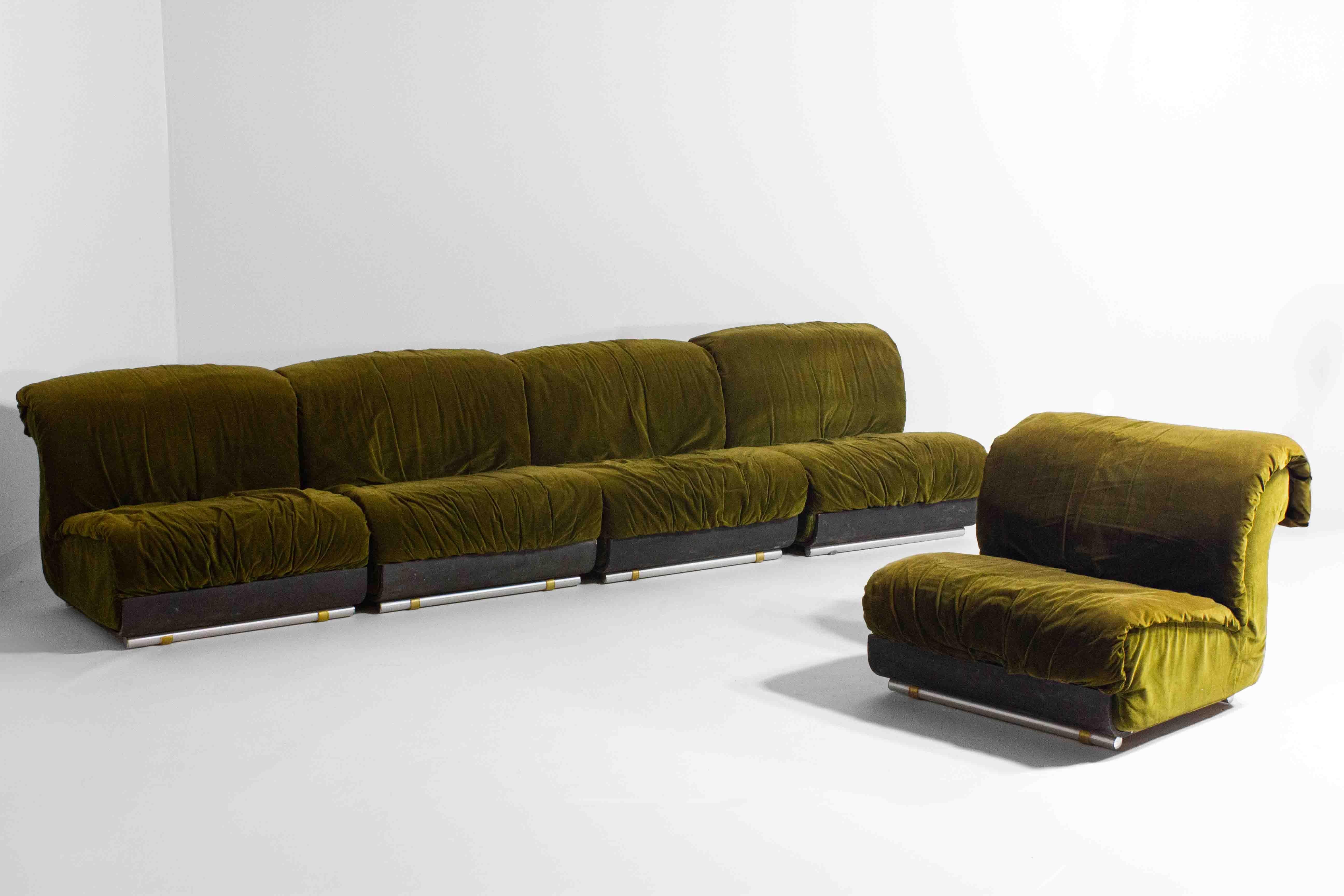 Il s'agit de  Le canapé italien modulaire des années 1970, recouvert d'un velours vert luxuriant, est composé d'une série de coussins individuels et dodus qui créent une ligne d'assise continue, chacun étant soutenu par un cadre métallique discret