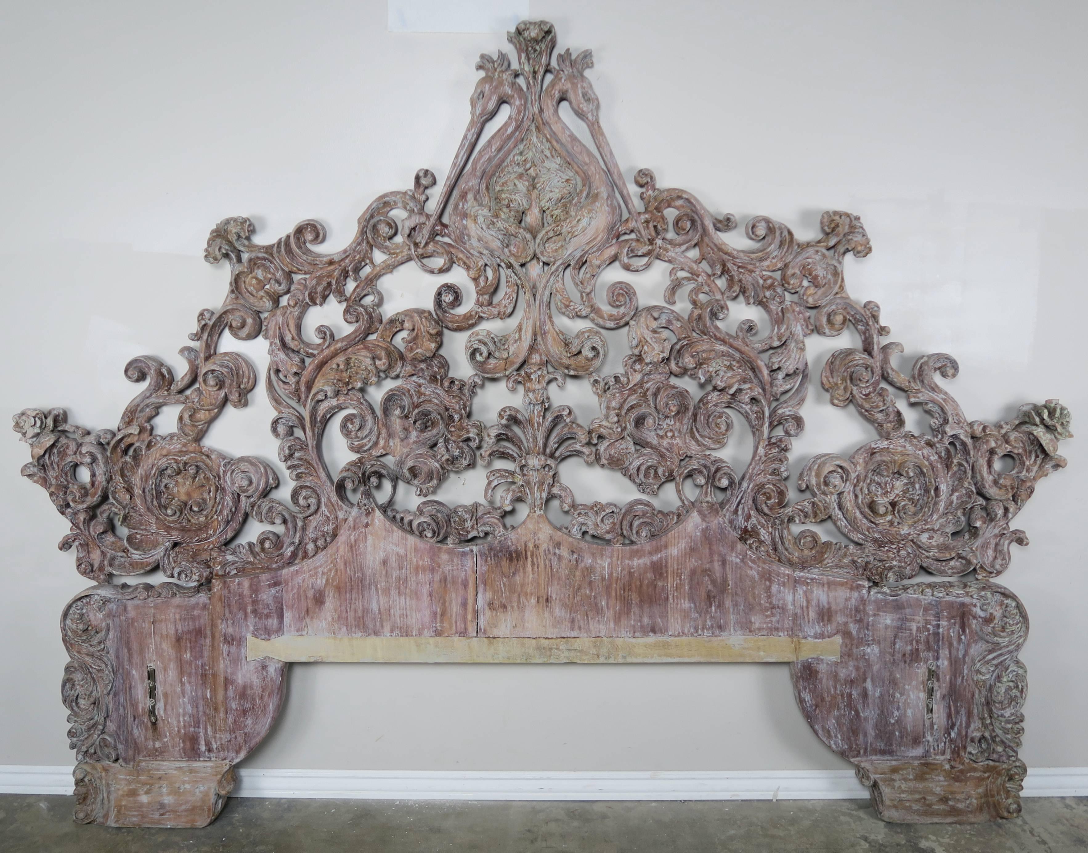 Italian carved wood Rococo style king-size headboard depicting swirling acanthus leaves throughout. Worn finish with remnants of paint can be seen.