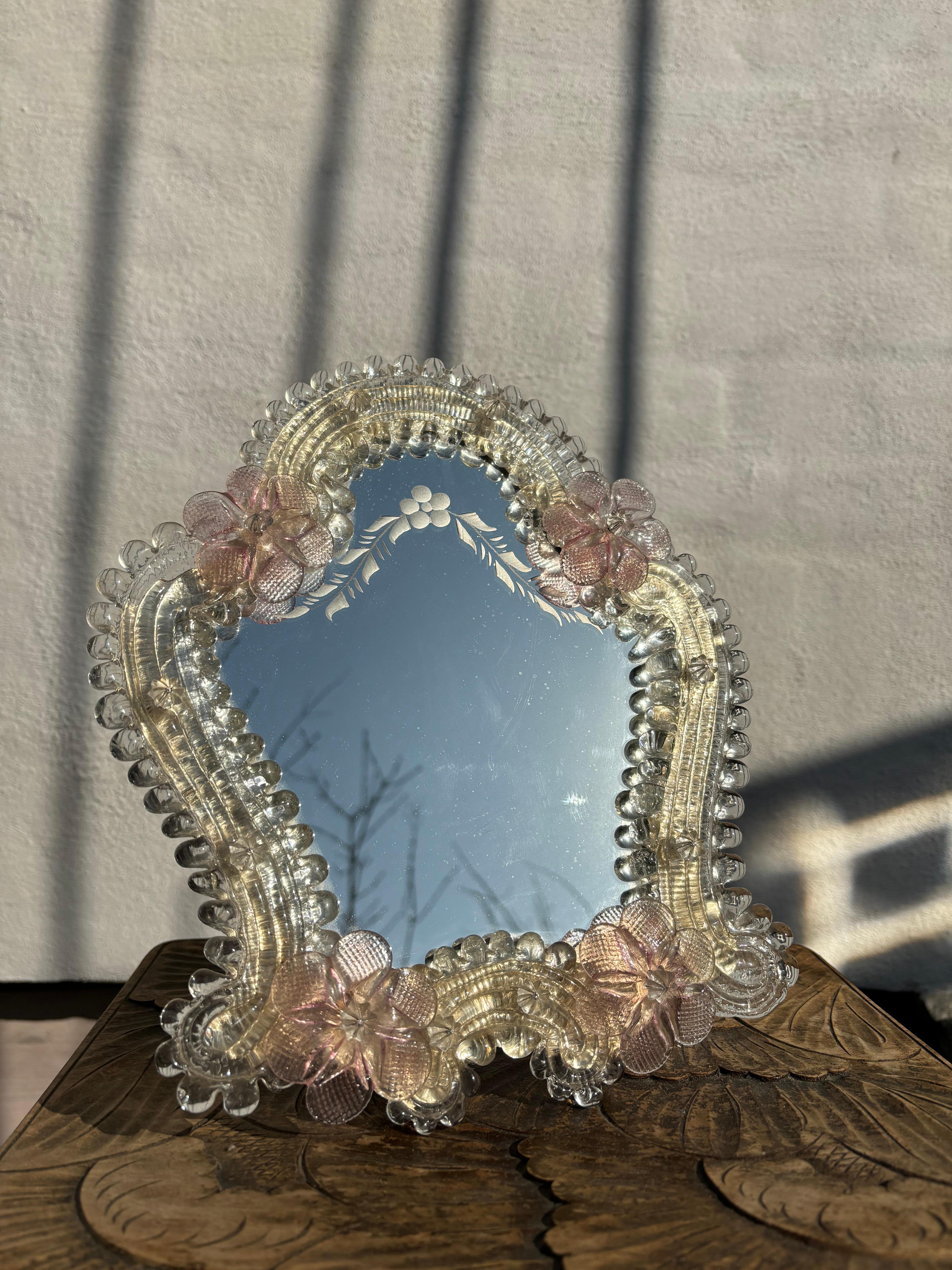 Vintage Venetian Murano glass dressing table / vanity wall mirror with floral etchings on the glass and a stunning art glass frame with clear and soft rose flower decorations. Mounted on wooden back with hinged table rest and metal easel for wall