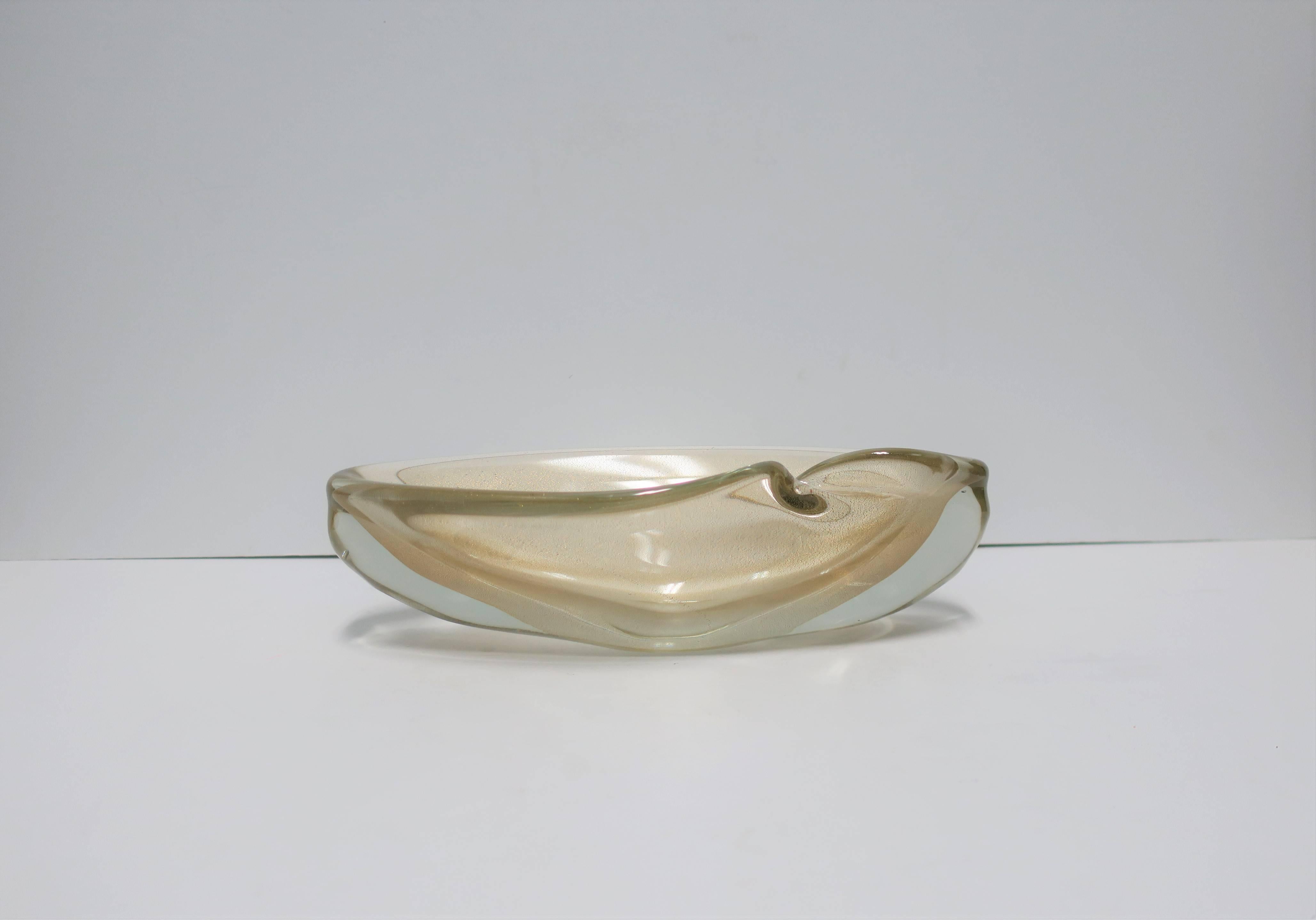 A beautiful and substantial Italian Murano oblong bowl. Bowl is clear Murano art glass mixed with shimmering gold, an intentional 'indent', and a soft and beautiful finish in an organic form. Attributed to Italian designer Seguso, Italy. Piece is