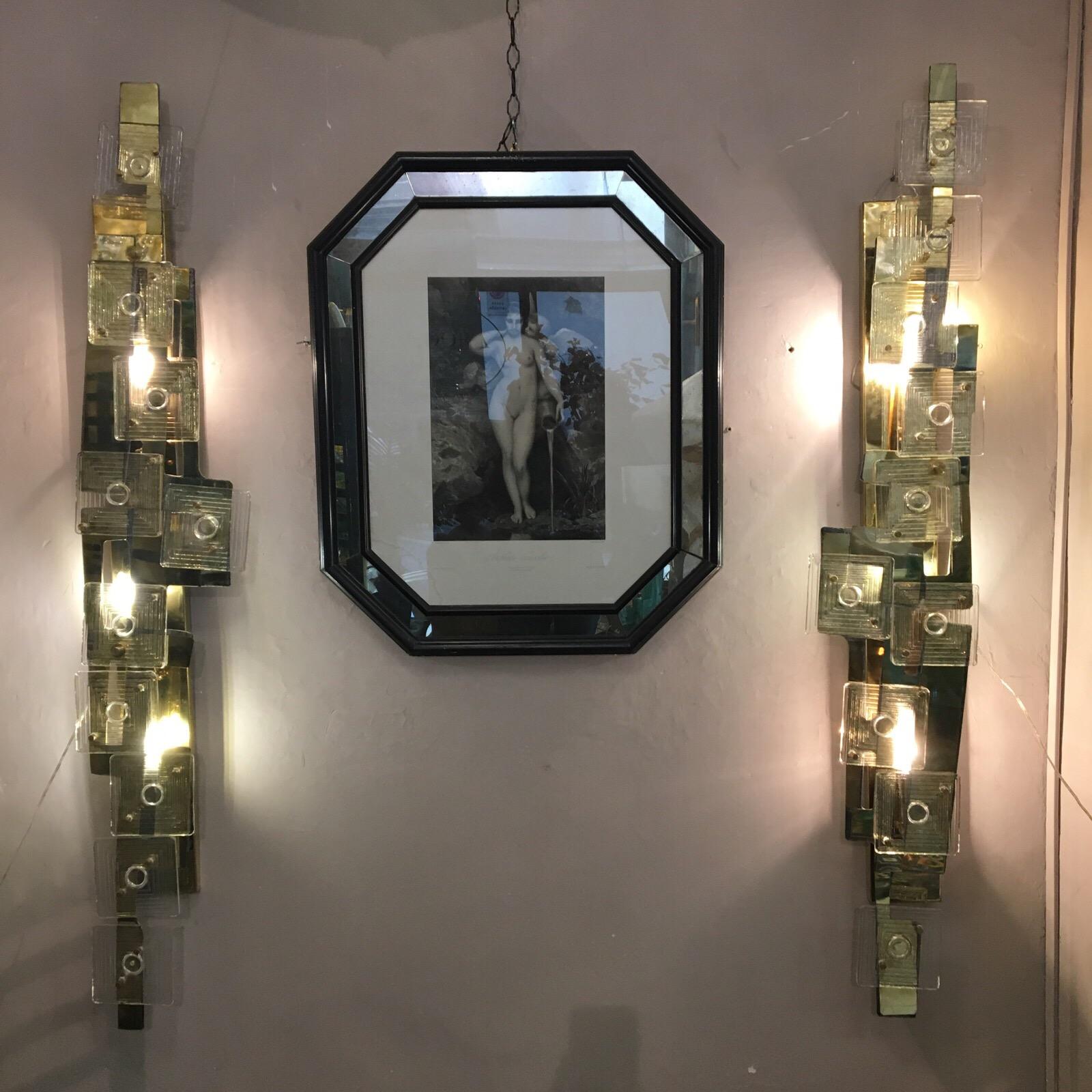 Italian Murano clear glass and brass tall wall sconces, iron structure, irregular shape covered with brass plate, decorated with vintage square Murano clear glass pieces, 4 bulbs per sconce.
