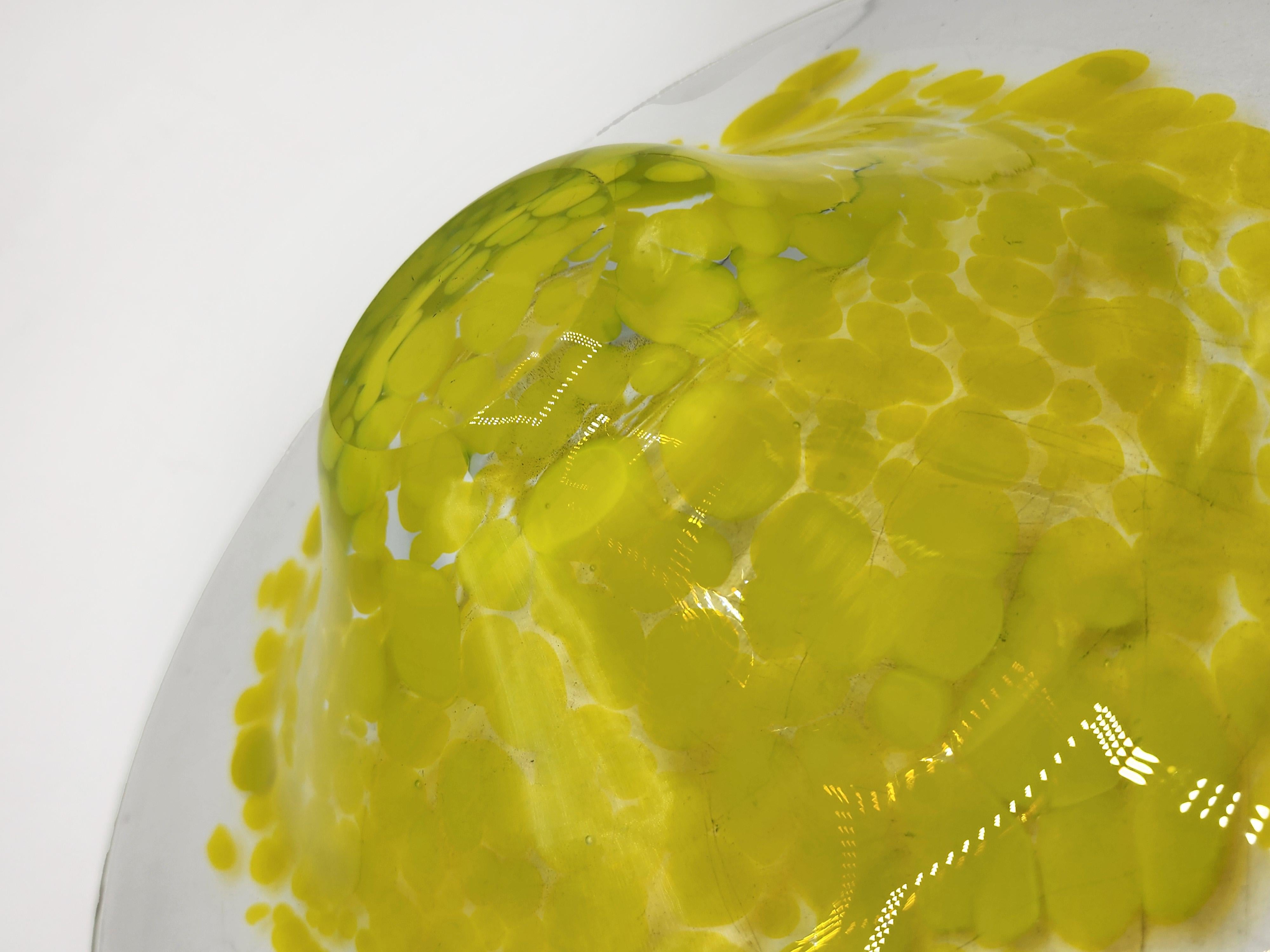 Italian Murano Decorative Plate from the 1970s
This Murano decorative plate, dating from the 1970s, features a circular shape with a slight indentation in the center, creating a shallow bowl. It is made of clear glass, with a layer of vibrant,