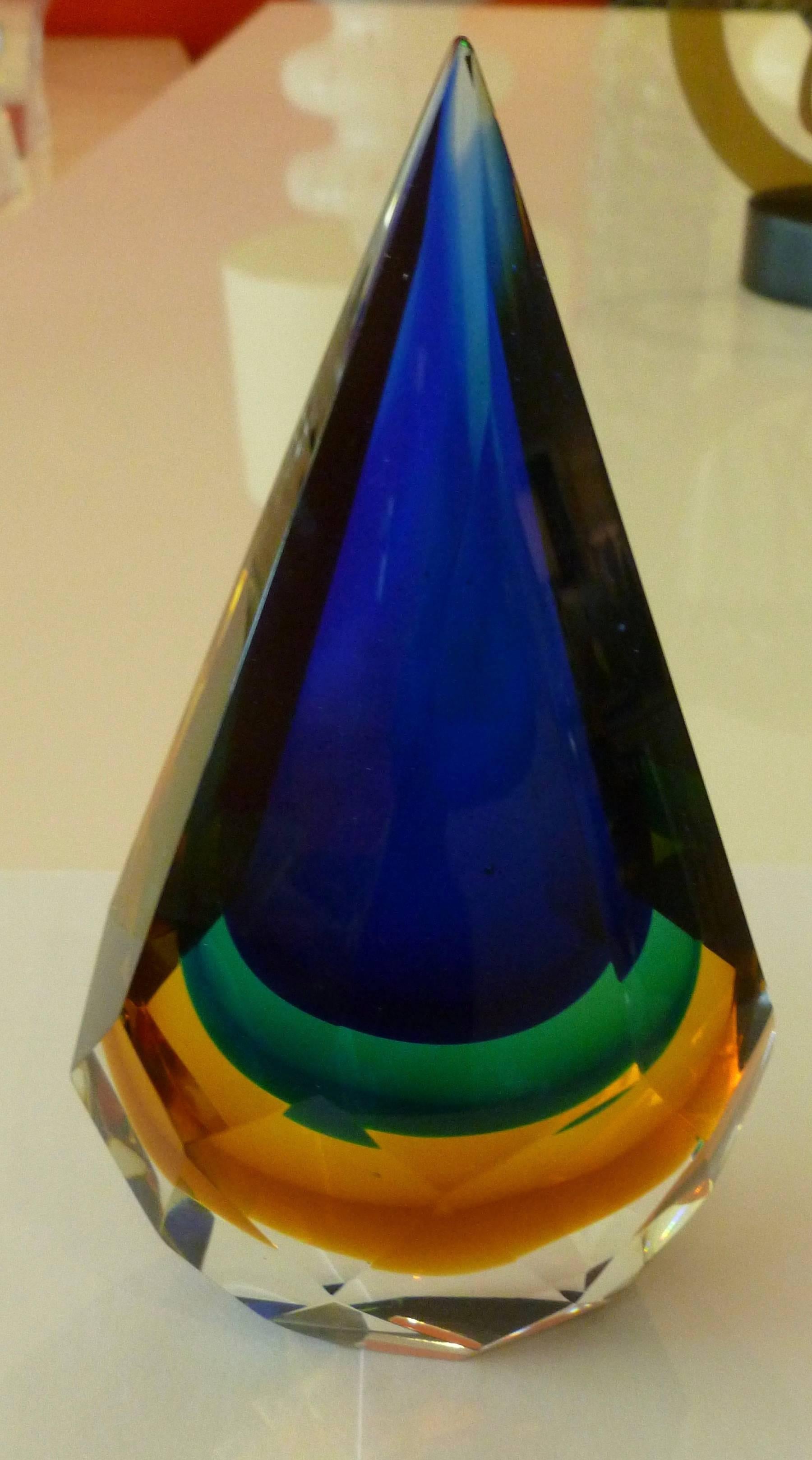This stunning and most unusual Italian Murano diamond faceted Sommerso glass paperweight /desk accessory glass sculpture are layers of colors of clear, amber, yellow, kelly green and brilliant royal blue. It has a pointed tip. It is the work of