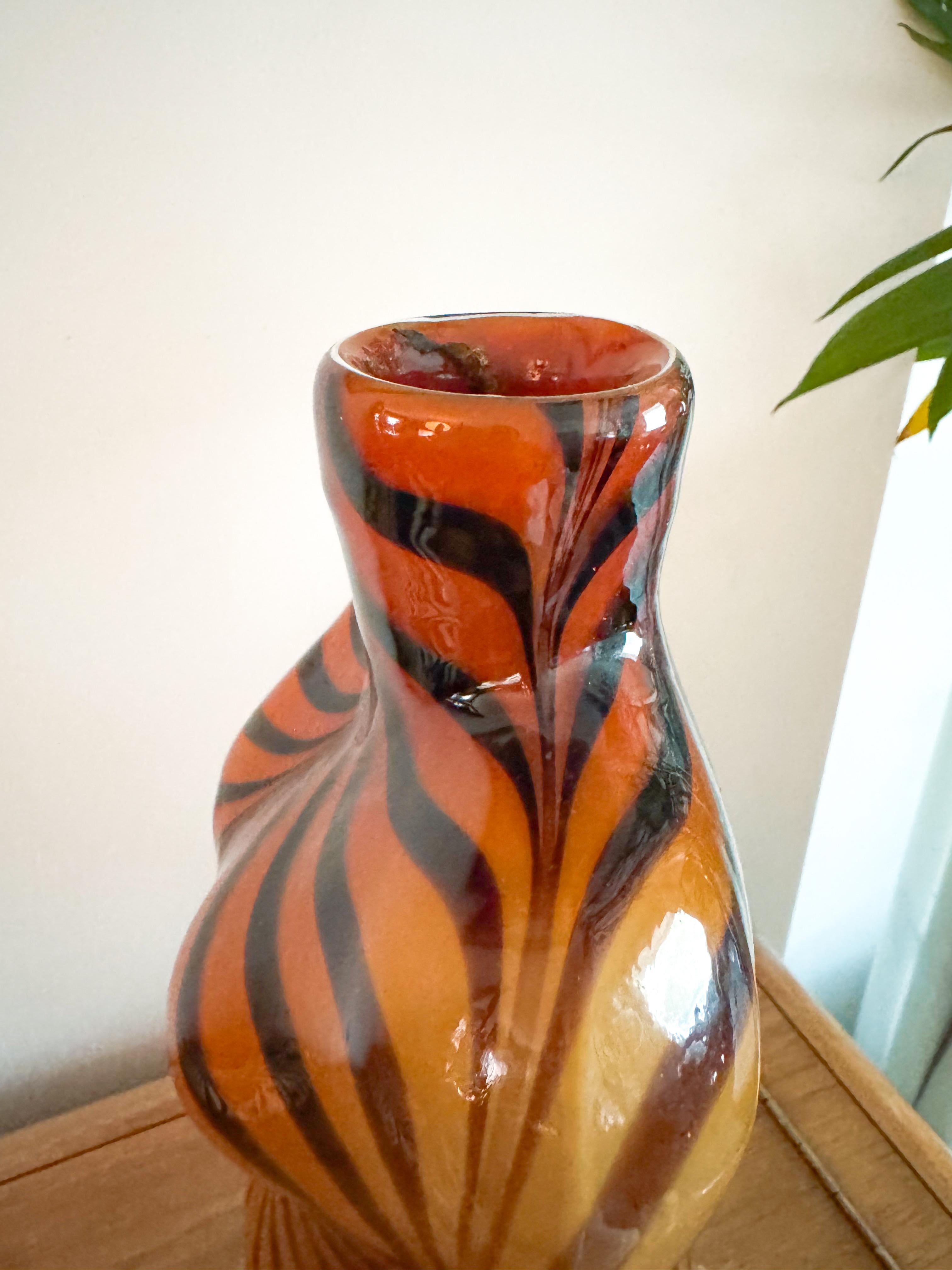 Vase sculptural en verre soufflé à la bouche en forme de torse féminin, fabriqué à Murano, Italie, vers les années 1980. Cette pièce est ornée d'un audacieux motif de rayures tigrées dans les tons ambre et noir, qui tourbillonnent de façon