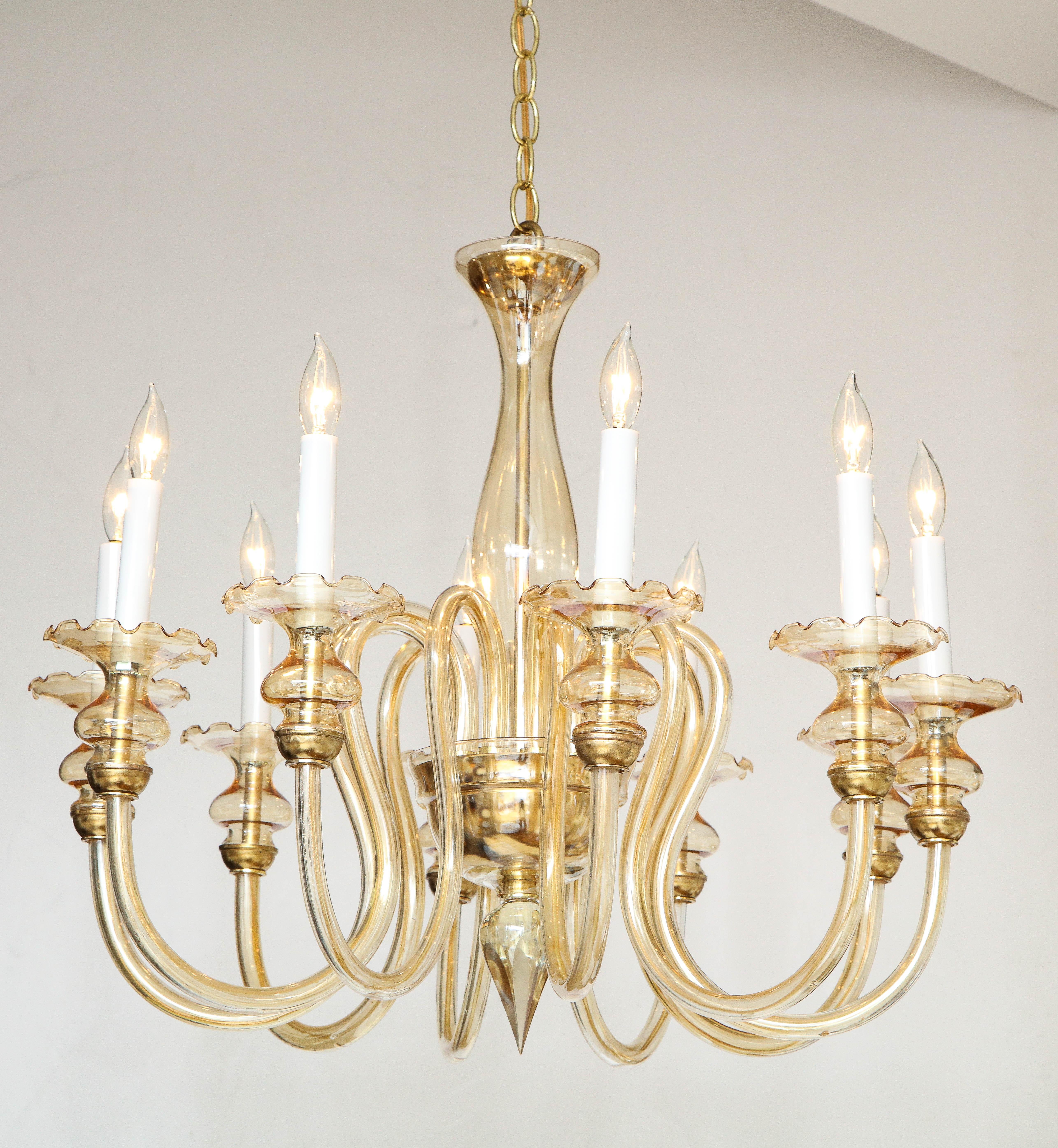 An Italian Murano 1950's hand blown glass ten arm chandelier; the bulb shaped center shaft supports the upturned ten arms which culminate with their lights surrounded by delicate glass scalloped motif and brass bobeche. The whole supported by a