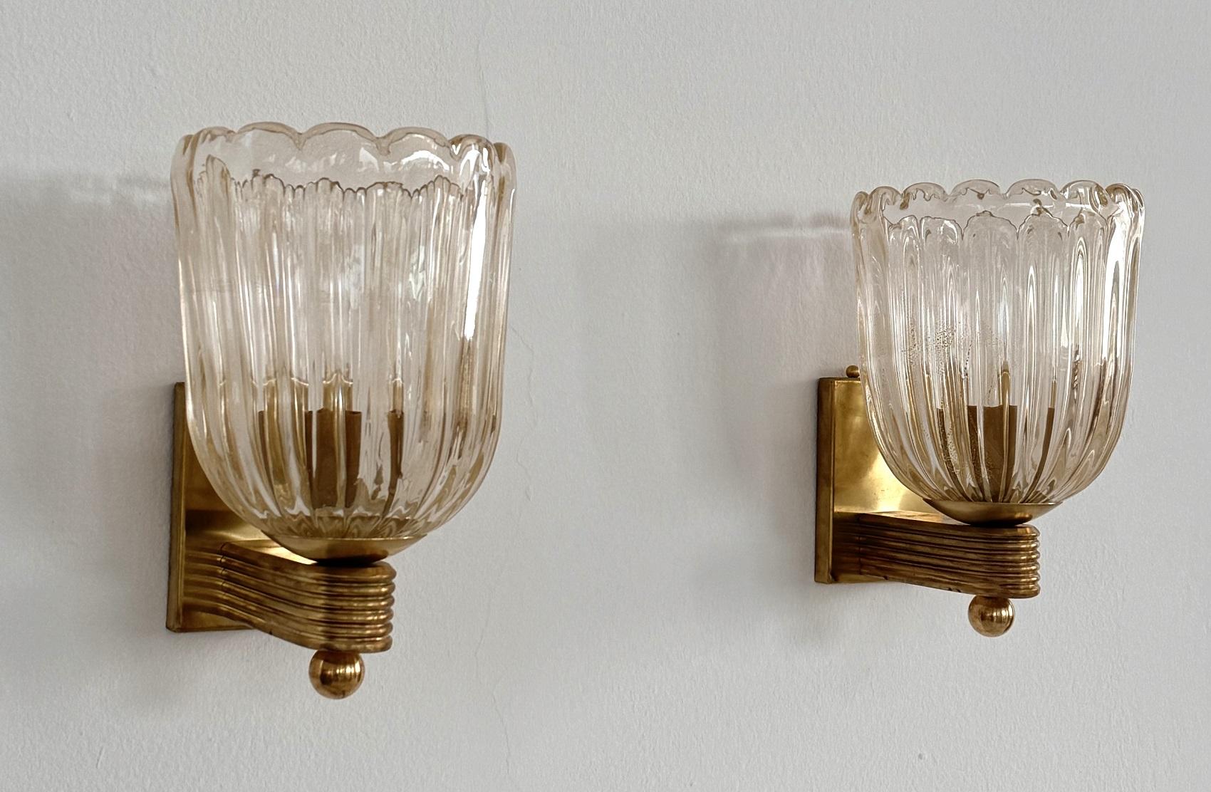Italienisches Murano Glas und Messing Wandleuchten Lights im Art Deco Stil, 1990er Jahre

Wunderschönes Set aus zwei prächtigen und schweren Wandleuchtern aus dickem Murano-Glas mit goldenem Schimmer/Glitter im Inneren des Glases und starkem