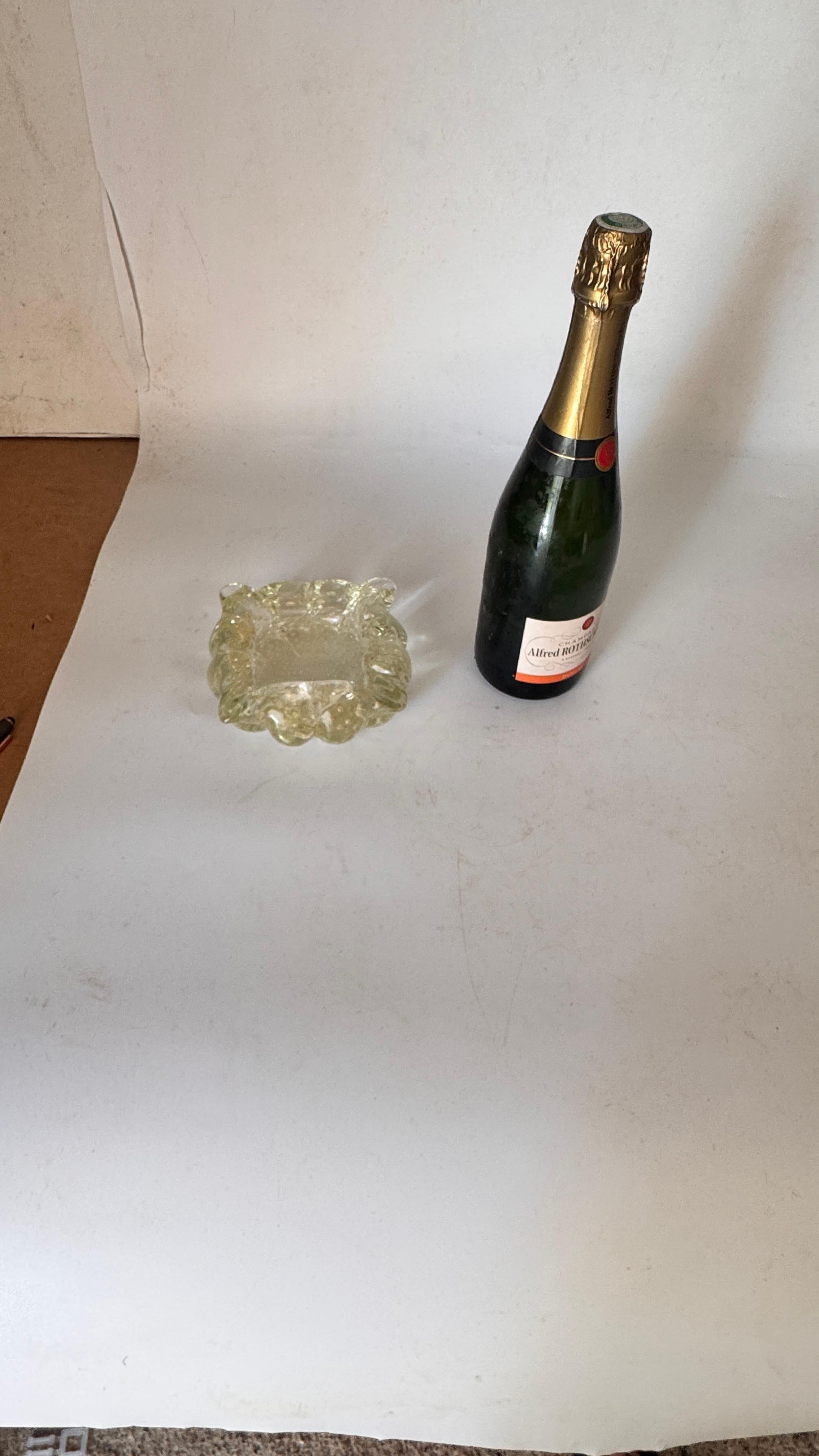 Italian Murano Glass Ashtray – 1960s – Anise Yellow, Hand-Blown with Air Bubbles

Description:
This is a hand-blown glass ashtray made in Italy in the 1960s, likely from a Murano glass workshop. The piece features a soft anise yellow hue, with color