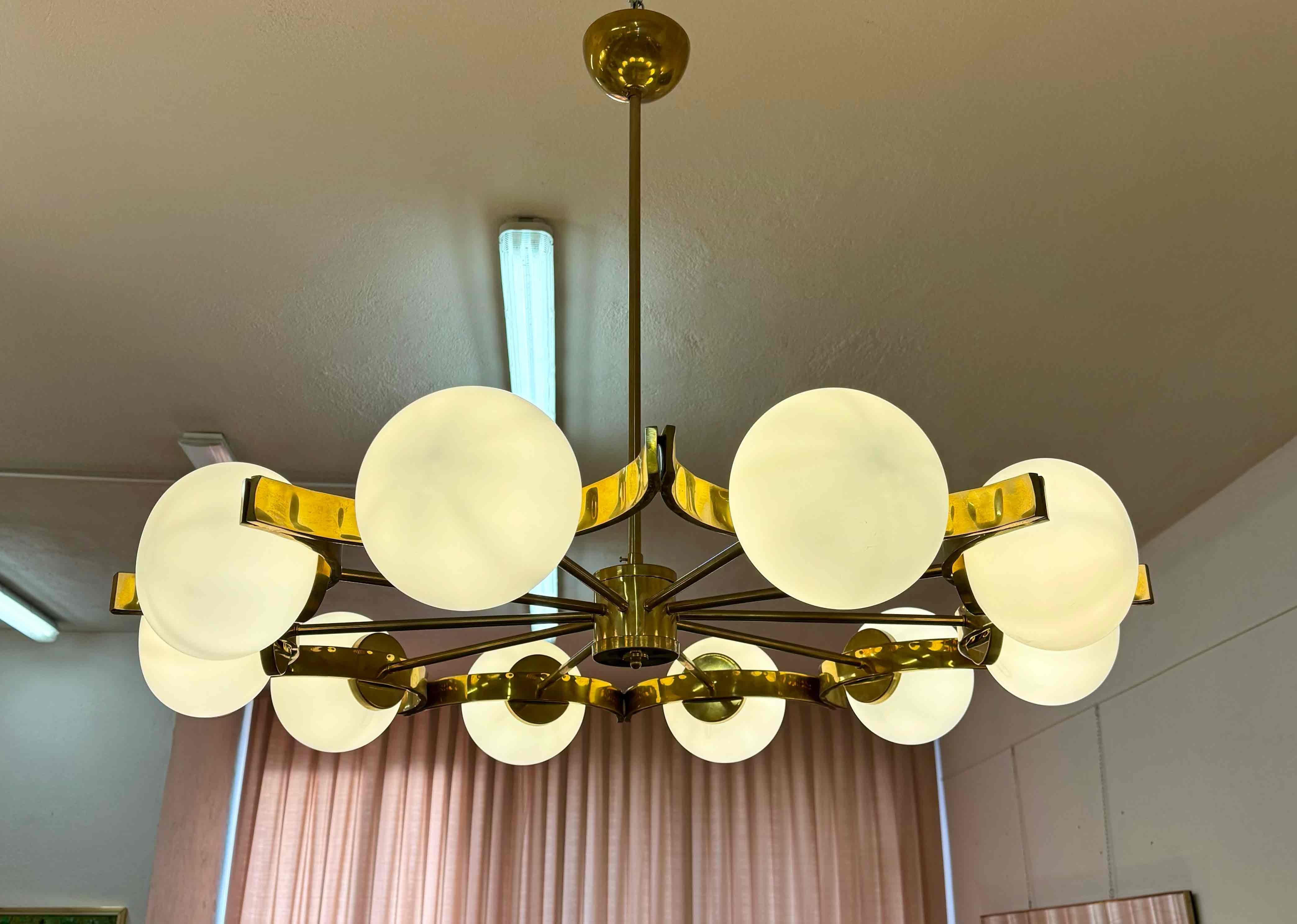 Elegant Italian chandelier handcrafted in Murano, featuring ten white Murano glass spheres arranged in a refined circular composition. The glass elements, finely worked by skilled Murano glass masters, diffuse a soft and warm light, creating a