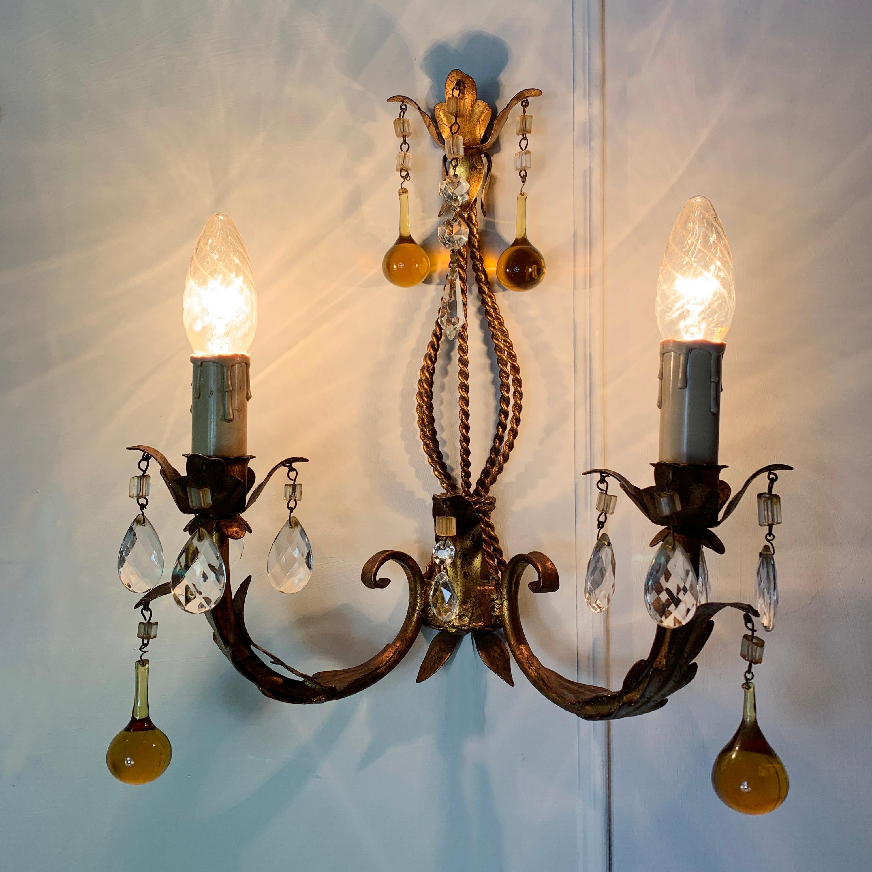 Italian Murano glass drop gilt wall light
Italy circa 1960s
Gilt leaves decorate the gilt rope detail central column
Large hanging hand blown golden Murano glass droplets are hung from the lampholders and top crown of the light
Smaller faceted