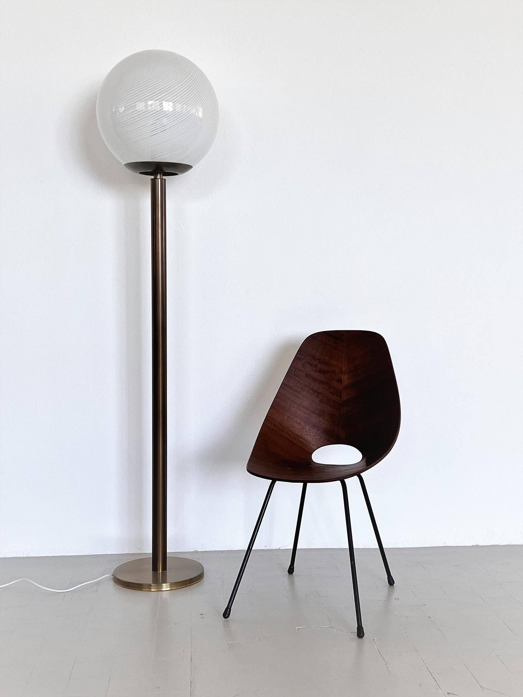 Tall Italian floor lamp with gorgeous hand-crafted round Murano glass sphere with shiny swirl white stripes.
The Glass reminds to Venini production.
When the lamp is switched on, the glass leaves beautiful stripes on near walls or surfaces.
The