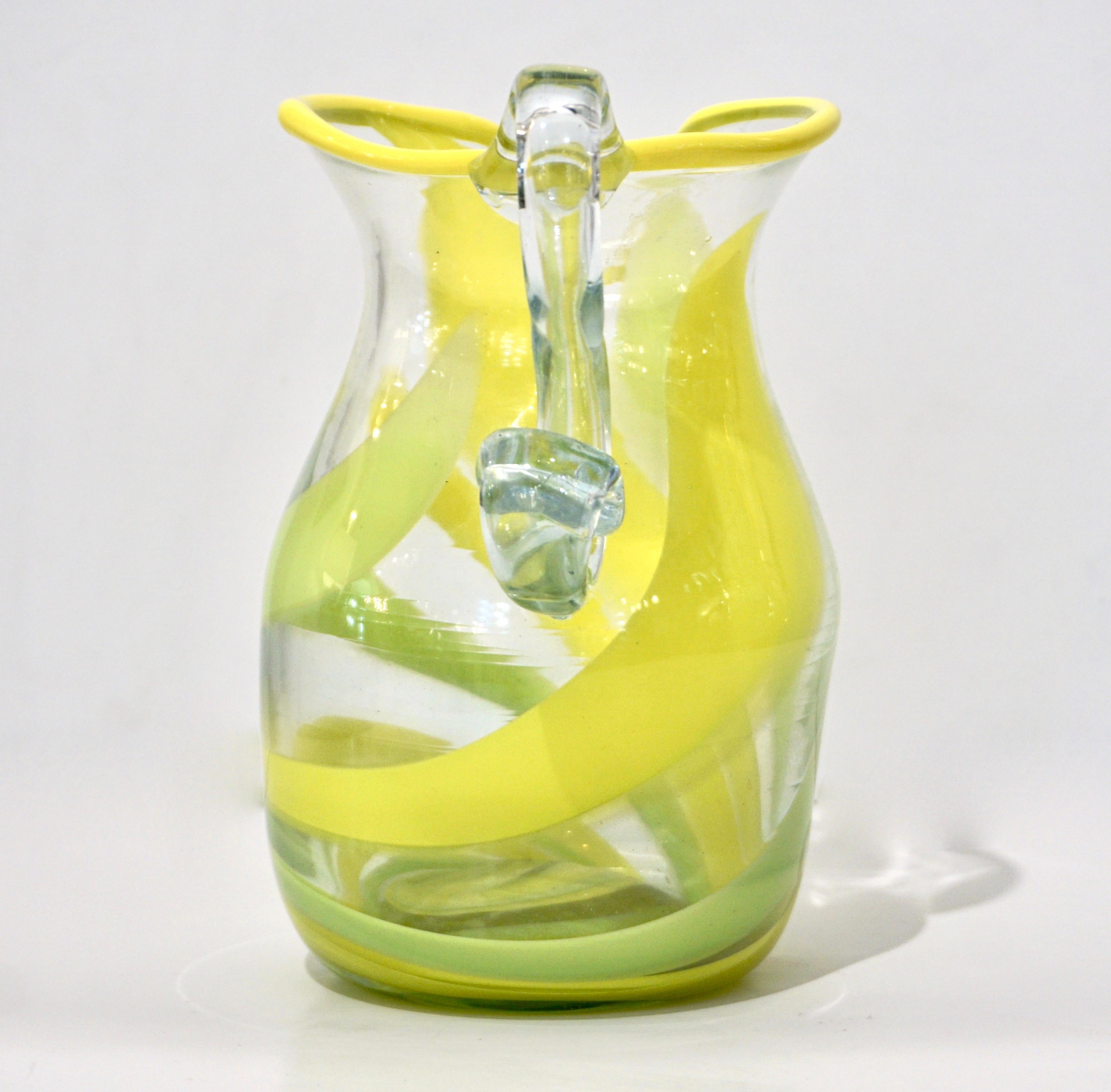 Venetian Handblown jug vase in clear blown Murano glass, with yellow and lime green filigrana swirls around the body. The handle is elegantly left in transparent crystal clear glass to reflect light and the rim of the jug is highlighted with a