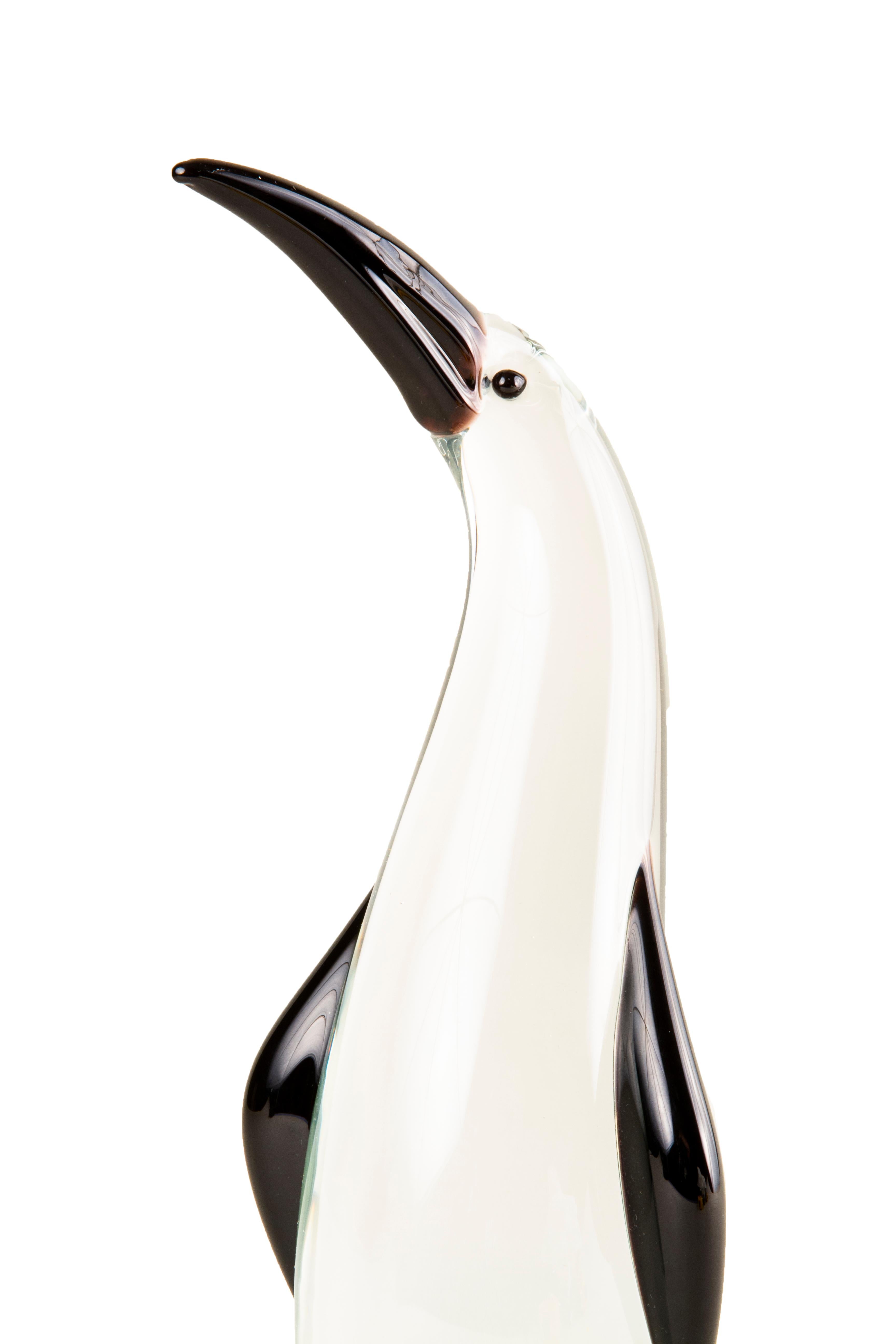 A whimsical Mid-Century Modern Italian blown art glass penguin sculpture attributed to Antonio da Ros, made for Cenedese decorated with heavy clear layered glass further decorated with an applied black/purple blown glass beak, flippers and eyes. The