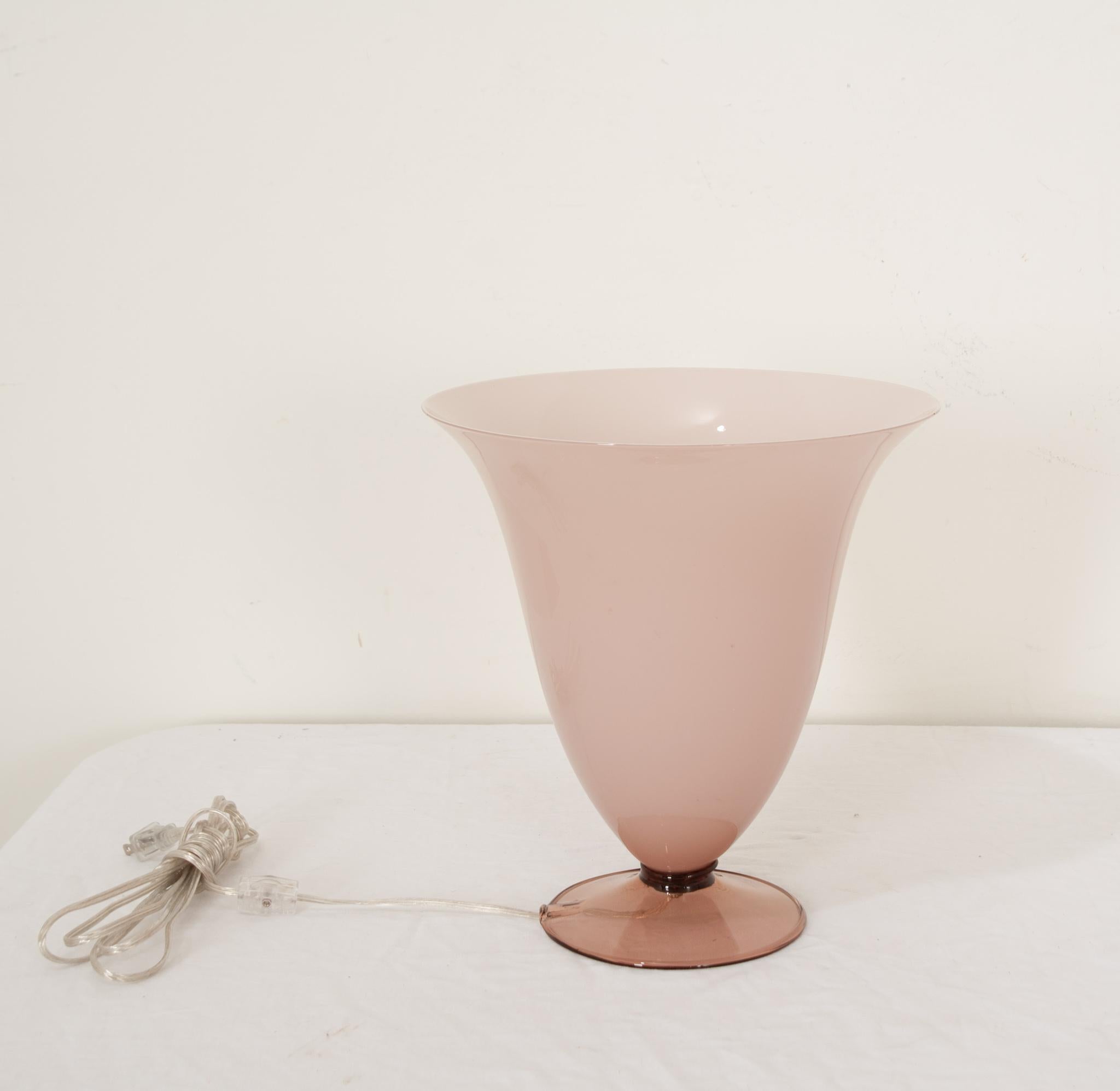 A vintage Italian Murano glass tulip shaped table lamp. Hand blown and very fine, it features a delicate pink translucent milk glass shade offset with a band of black detailing around a lustrous transparent l’aubergine colored base.  The bottom of