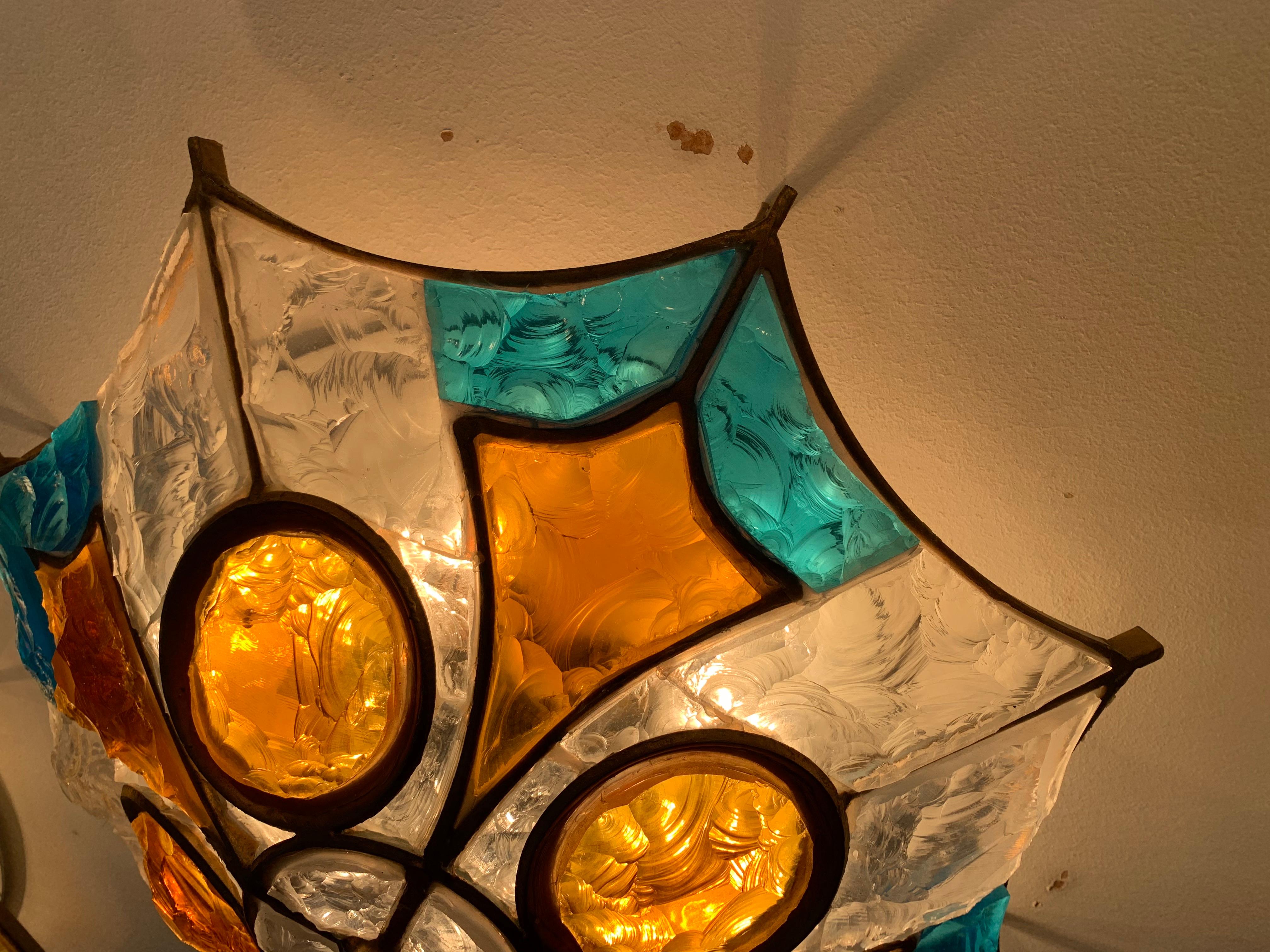 Applique en verre de Murano conçue et fabriquée par Longobard en 1970. La structure est en fer forgé doré travaillé à la main avec l'insertion d'un épais verre martelé coloré.
 
 
   