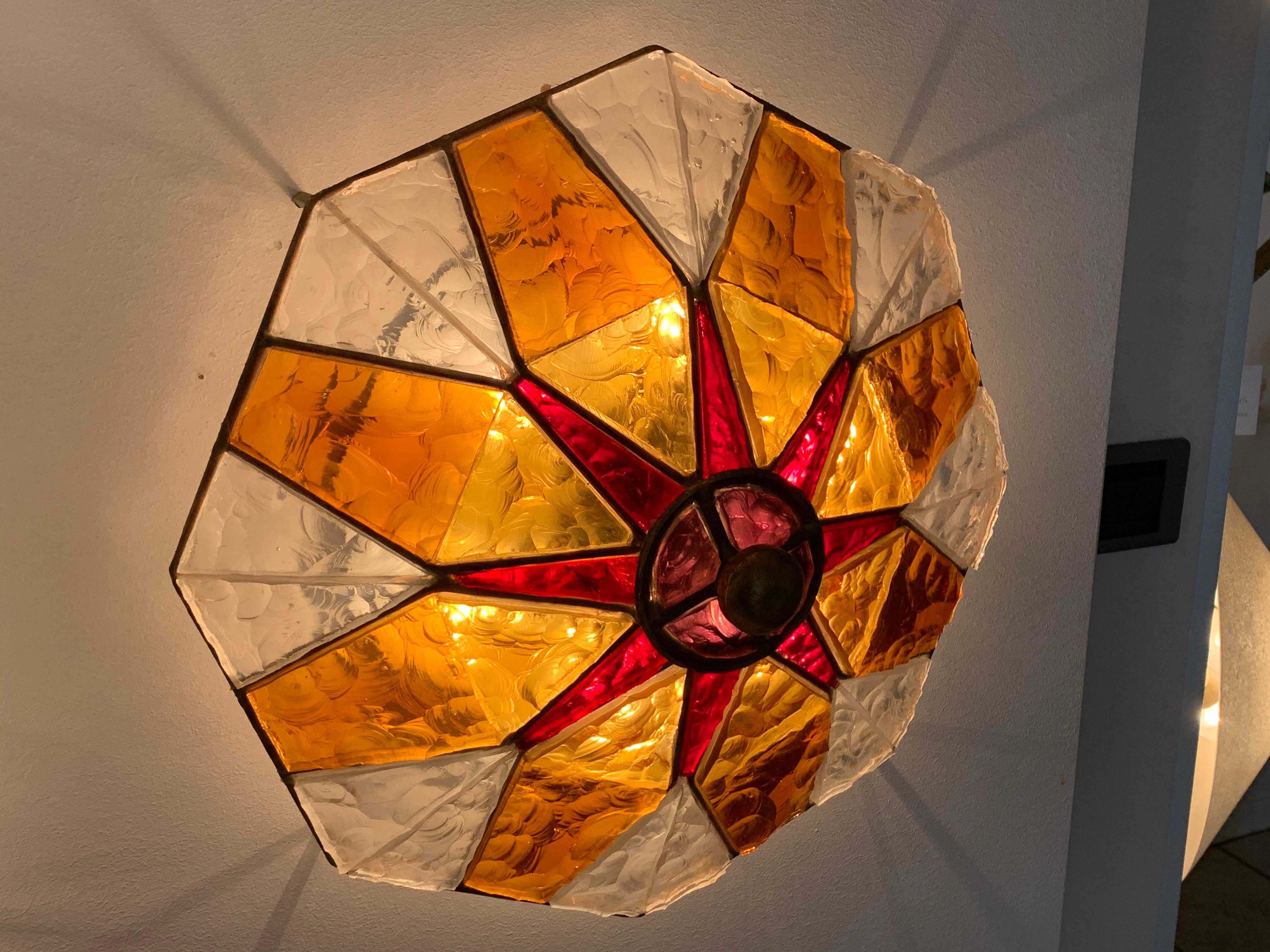 Murano glass wall lamp designed and manufactured by Longobard in 1970. 
The structure is in hand-worked golden wrought iron with the insertion of thick colored hammered glass.
 
  
  