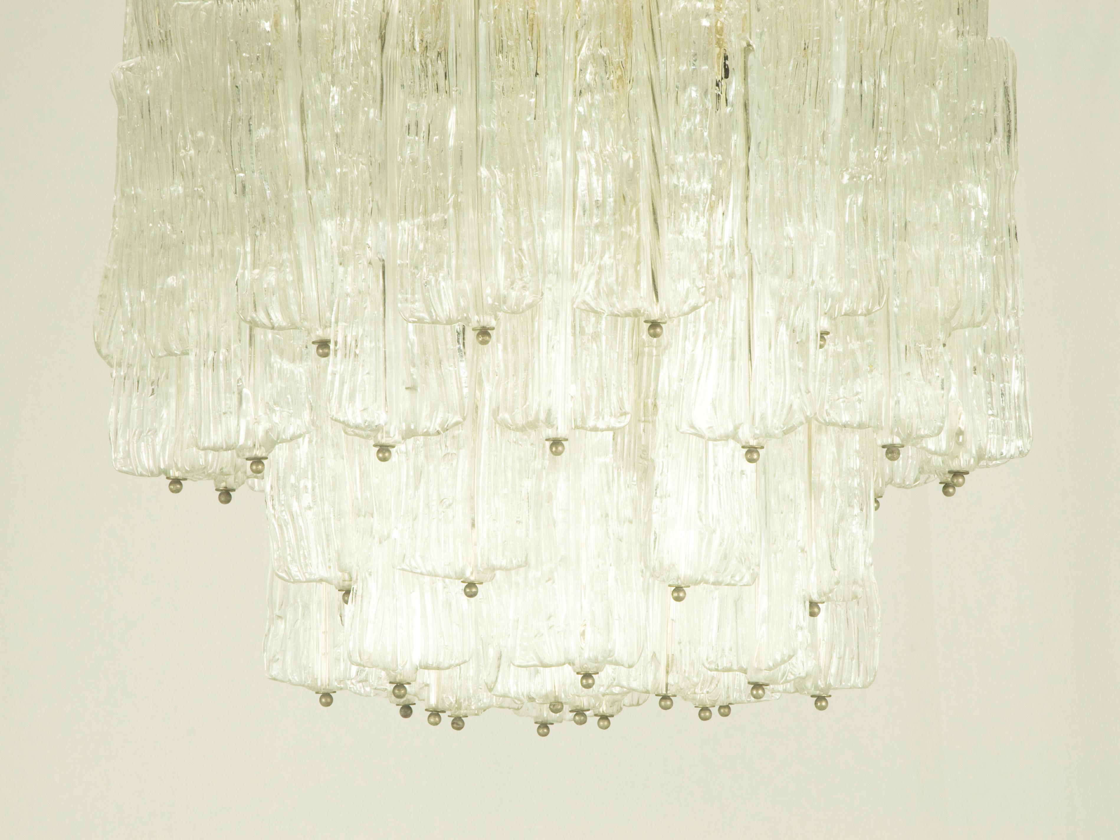 This rare chandelier was produced in Italy by the famous glassworks Venini, circa 1960s. It is made from 51 handmade pieces of transparent glass hung on the painted metal structure. Venini mark imprinted by maker on the metal frame. 
The chandelier