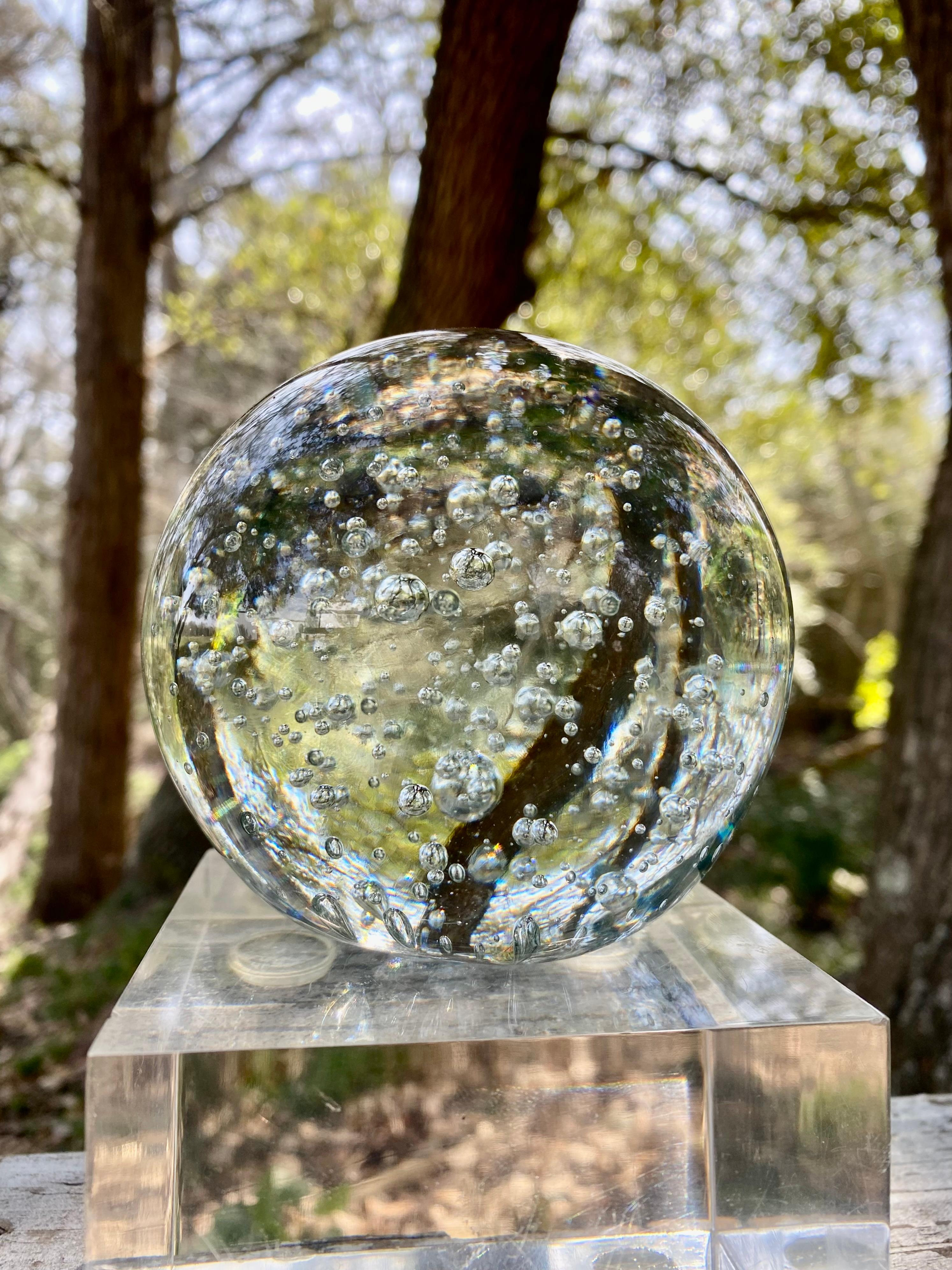 Un presse-papier boule en verre de Murano à couper le souffle, soufflé à la main de manière exquise et orné de bulles hypnotiques, semblant suspendues dans le temps. Cette pièce remarquable, attribuée à la légendaire tradition verrière de Murano,