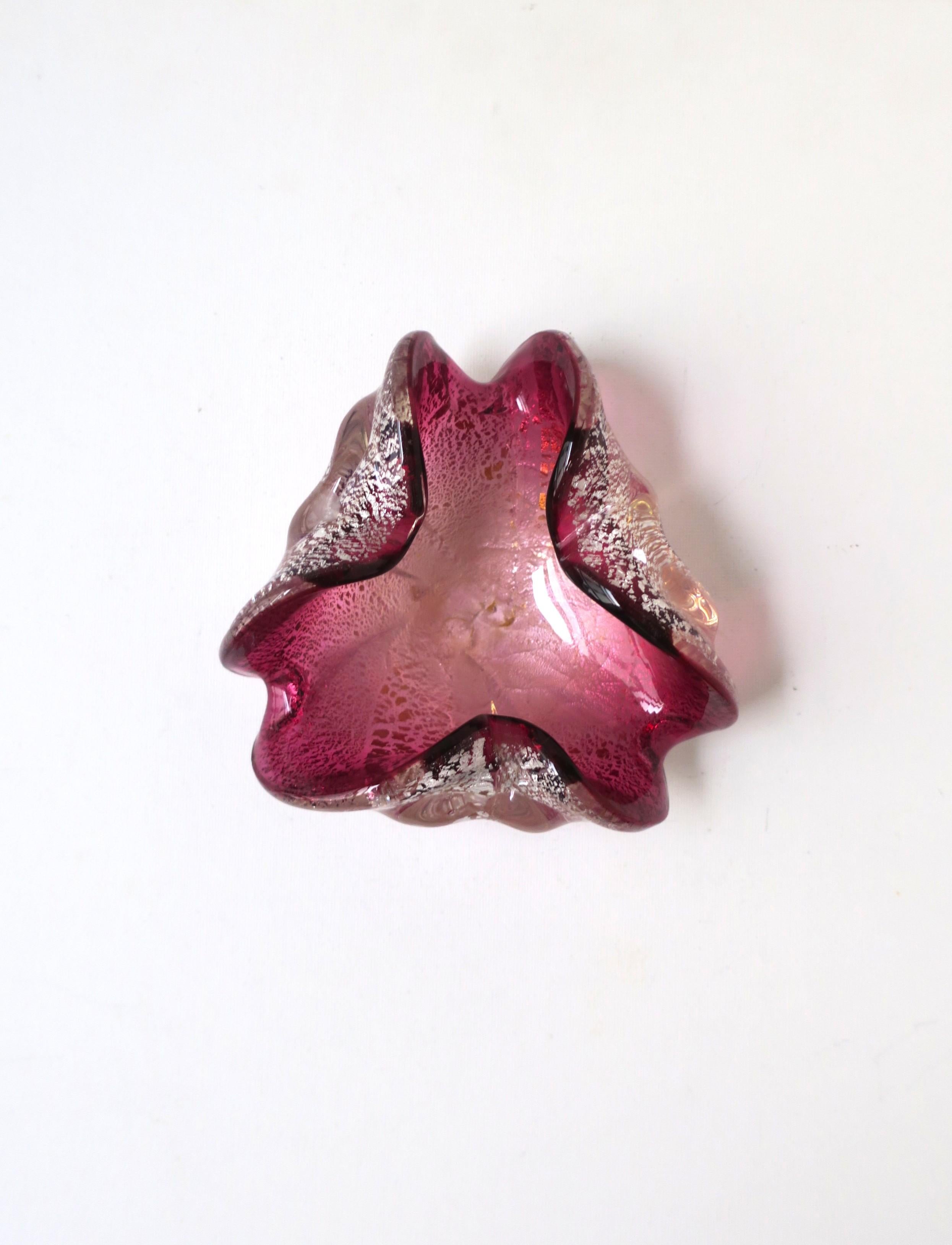 A beautiful Italian Murano art glass bowl in a magenta pink/aubergine hue with a substantial amount of silver leaf, finished with a clear/transparent exterior, and soft edges all around, Mid-Century Modern period, circa mid-20th century, Italy.