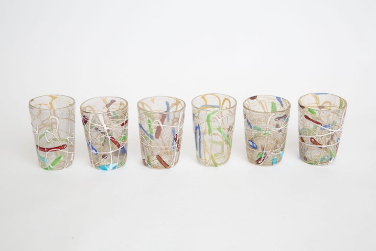 These vintage Italian murano hand blown tumblers are great barware and a set of 6. They have applied swirls of textural glass on the outside of white and gold. There is gold aventurine throughout. The the colors range from abstractions of turquoise,
