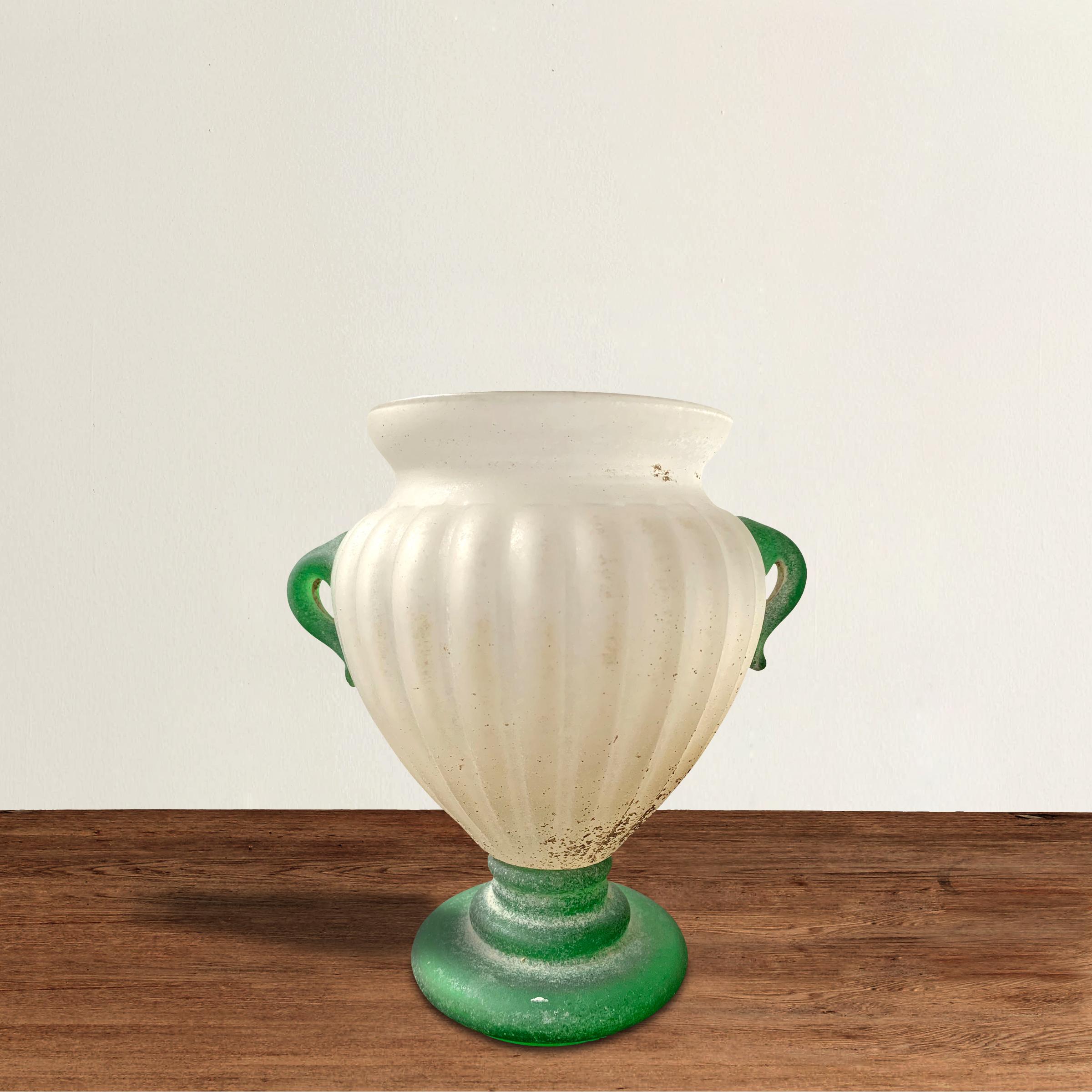 A mid-20th century Italian Murano blown scavo glass vase of Classical Roman form with two green glass handles applied to an opaque white fluted vase resting a tiered green glass foot. Scavo is Italian for 