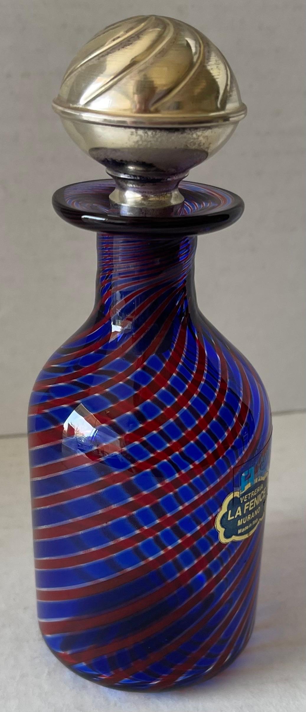 Bottiglia per profumo in vetro soffiato italiano La Fenice Murano. Vetro blu, rosso e trasparente con tappo in argento. La bottiglia conserva tutti gli adesivi del marchio e il tappo è stampato, come mostrato nelle foto. 
