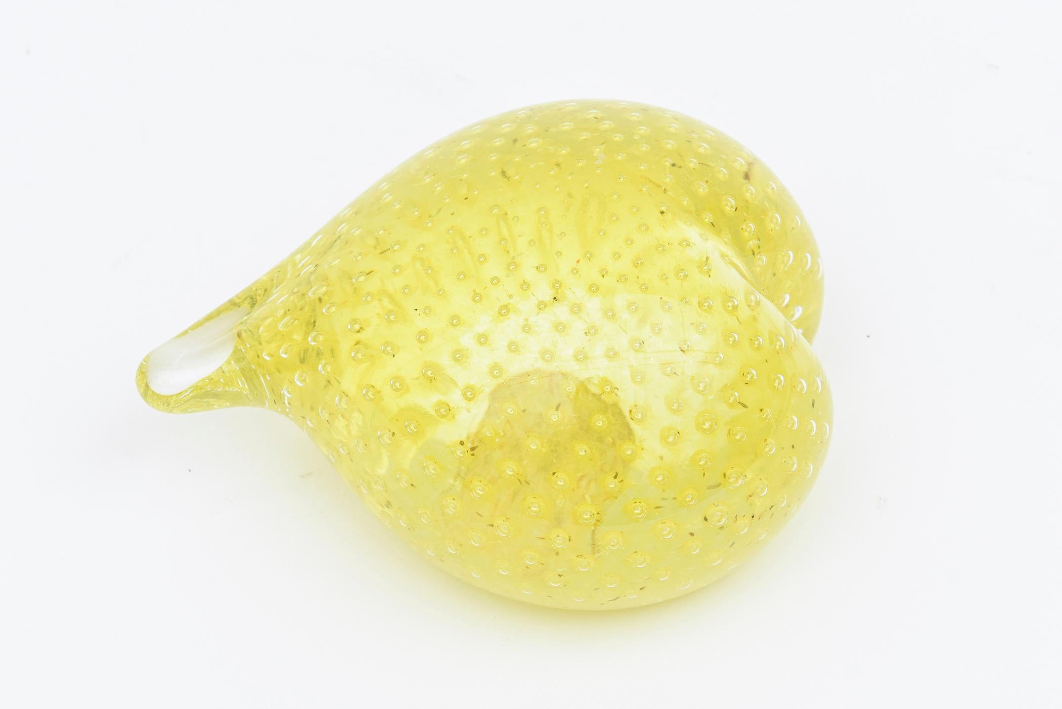 This gorgeous and happy vintage Italian Mid-Century Modern hand blown glass Murano paperweight and desk accessory has a sensual form in the shape of a heart. The light yellow color with bubbles and the original paper label on the bottom date the