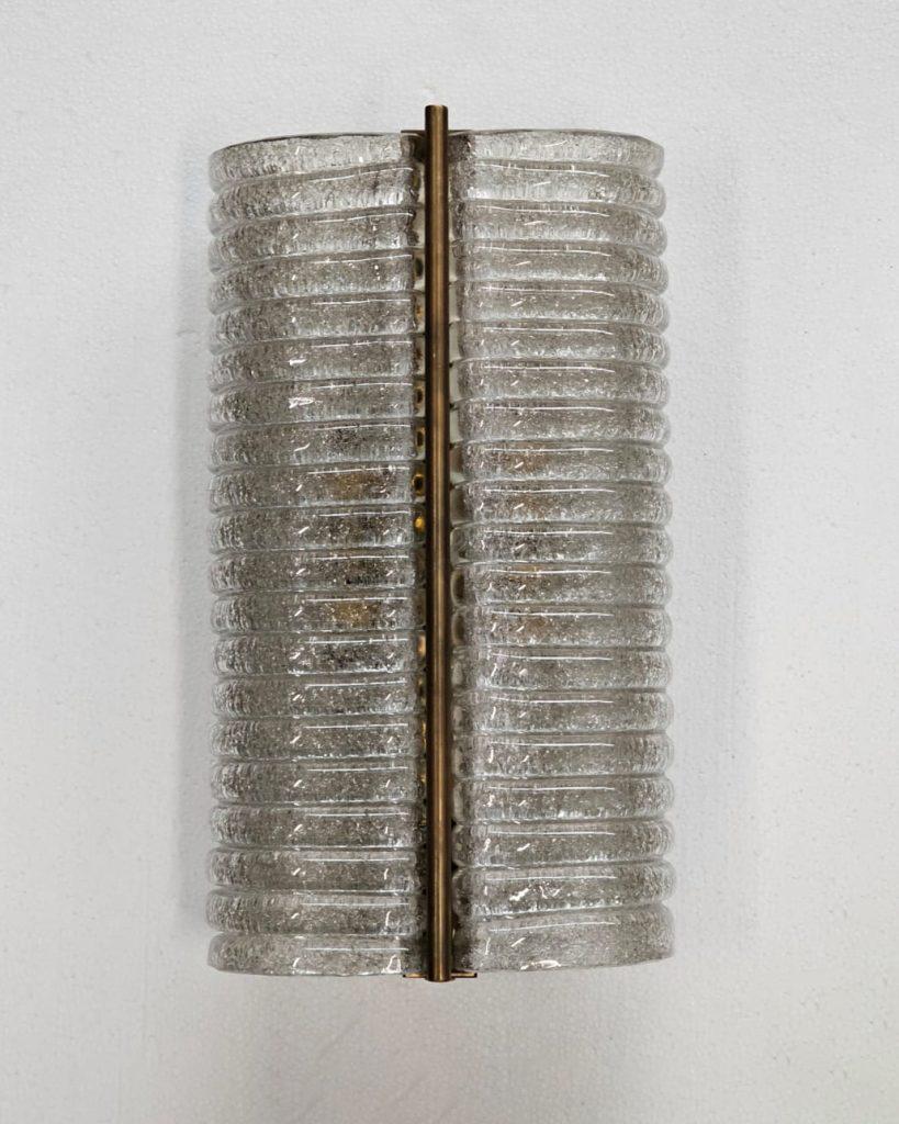 Italian Murano Wall Sconces made by eModerno, meticulously created in Italy to meet the highest standards of quality.
Clear ribbed crushed Murano glass in a cylinder shape with a central bronze stem.
Made by hand in Venice, each sconce is unique and