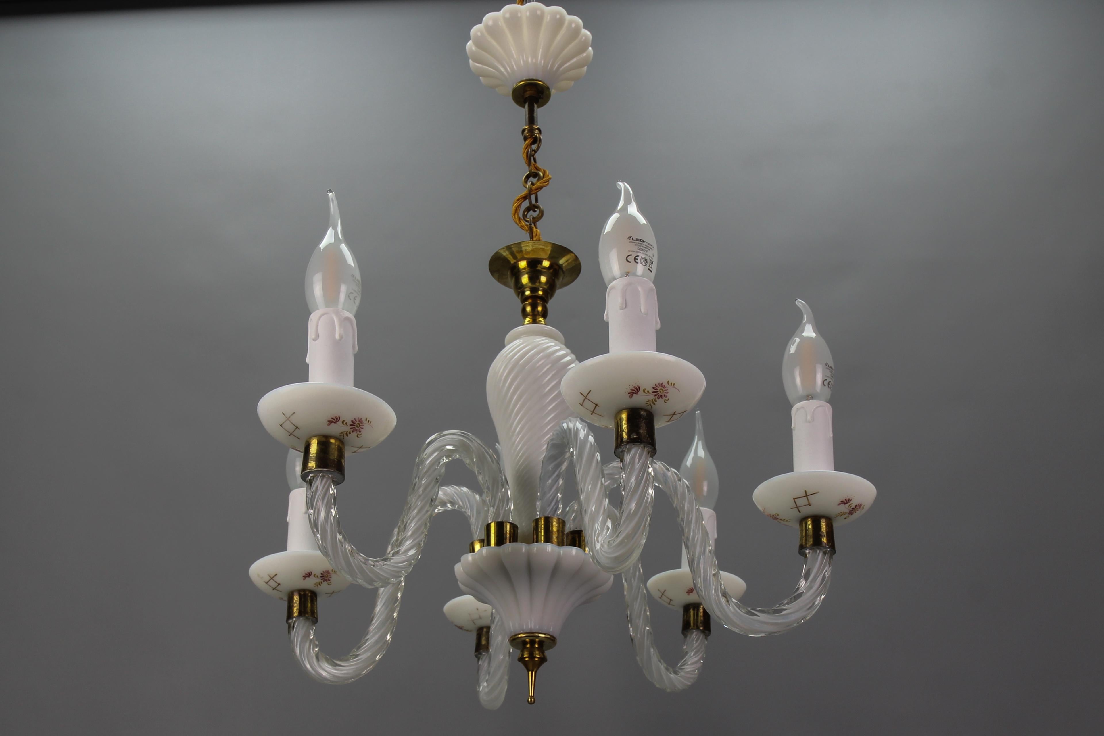 Italian Murano white milk glass and clear glass six-arm chandelier, the 1950s
This absolutely delightful Mid-Century Murano glass chandelier features six clear and milk glass arms with brass details and white milk glass bobeches with floral