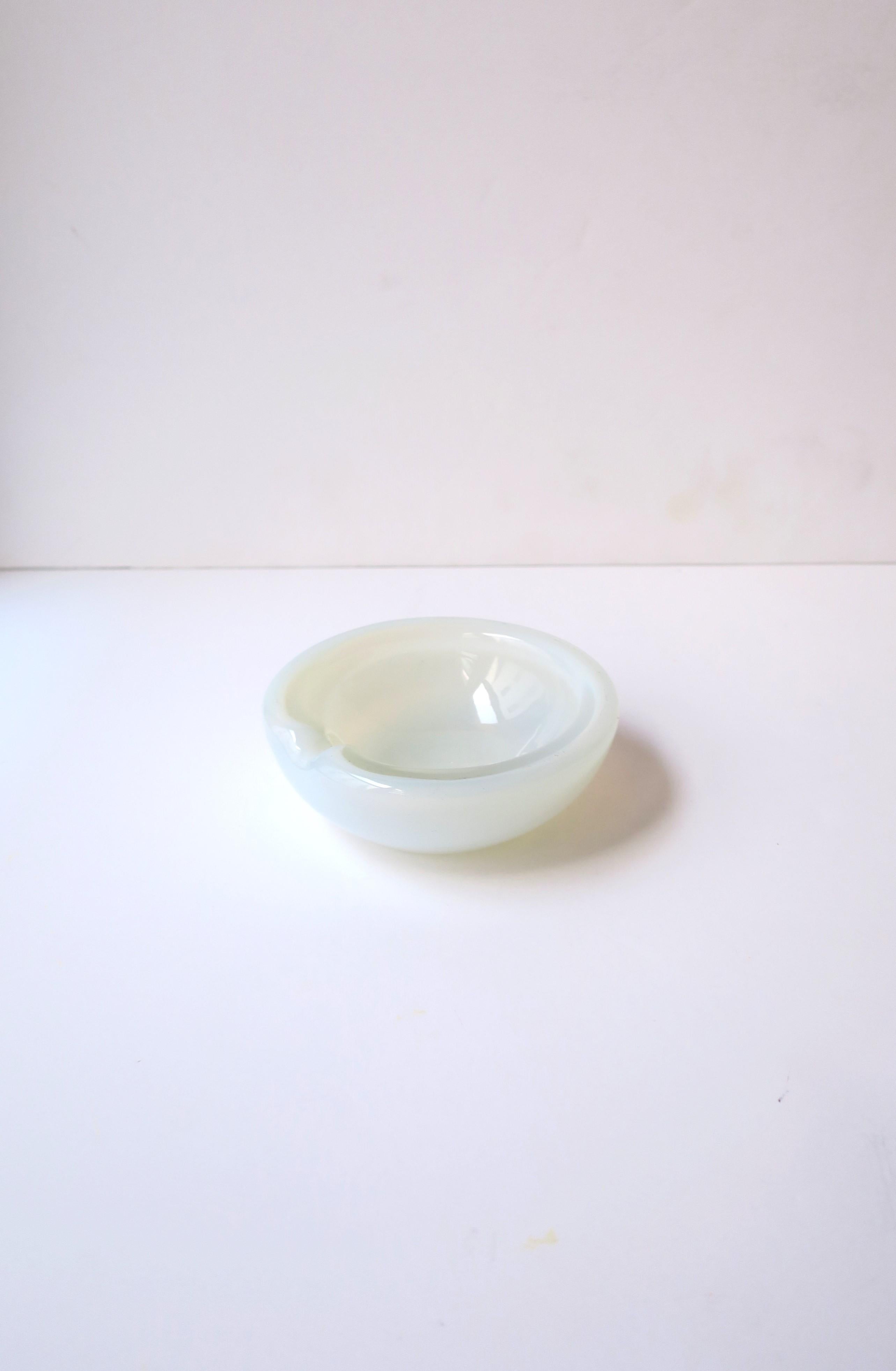 An Italian Murano white opaline art glass ashtray or bowl, Midcentury Modern period, in the style of designer Angelo Seguso, circa mid-20th century, Italy. A beautiful small ashtray with one indent around edge. Piece also makes a great bowl or