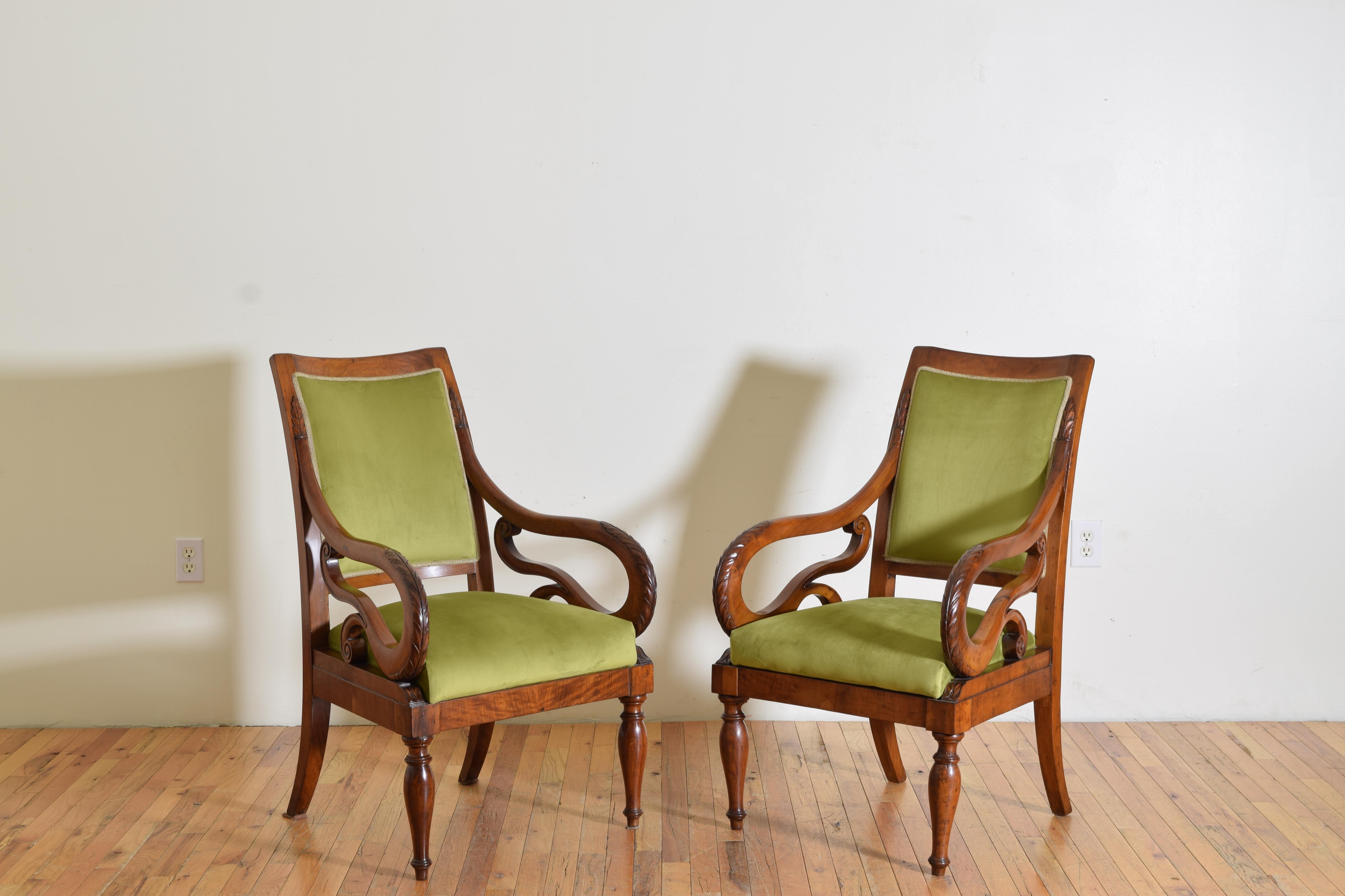 The chairs having flared backrests with slightly concave tops, the flare continuing at the rear block legs, the elaborately shaped and carved arms resting on square frames raised on elegantly turned front legs, upholstered in velvet
