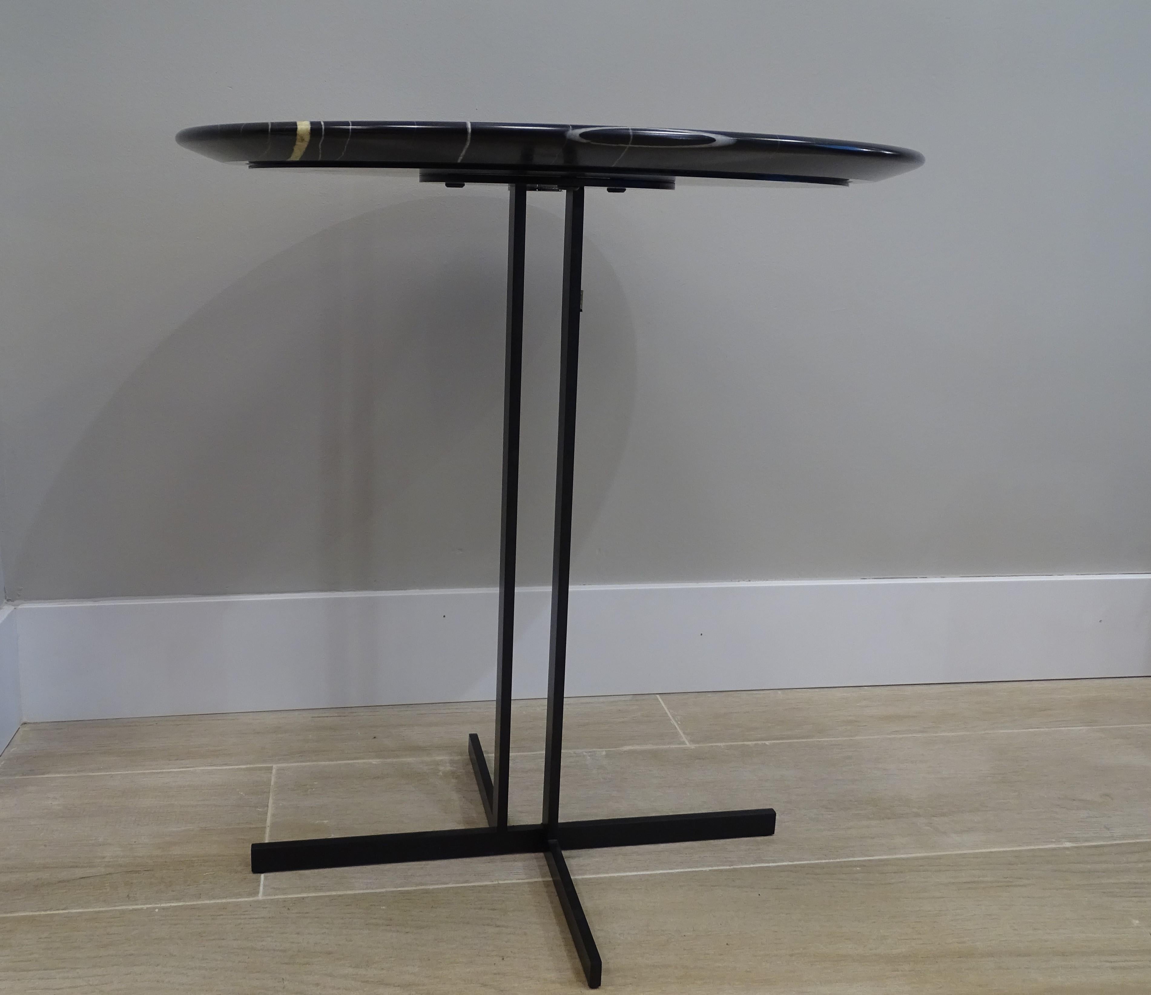 Elegante e bellissimo tavolino da caffè di Natuzzi Modello ESTRO E028. Ha un design semplice, un piano circolare in marmo e una struttura in metallo con finitura Black Brunito. Il marmo Sahara Noir è di colore nero intenso con venature bianche, oro