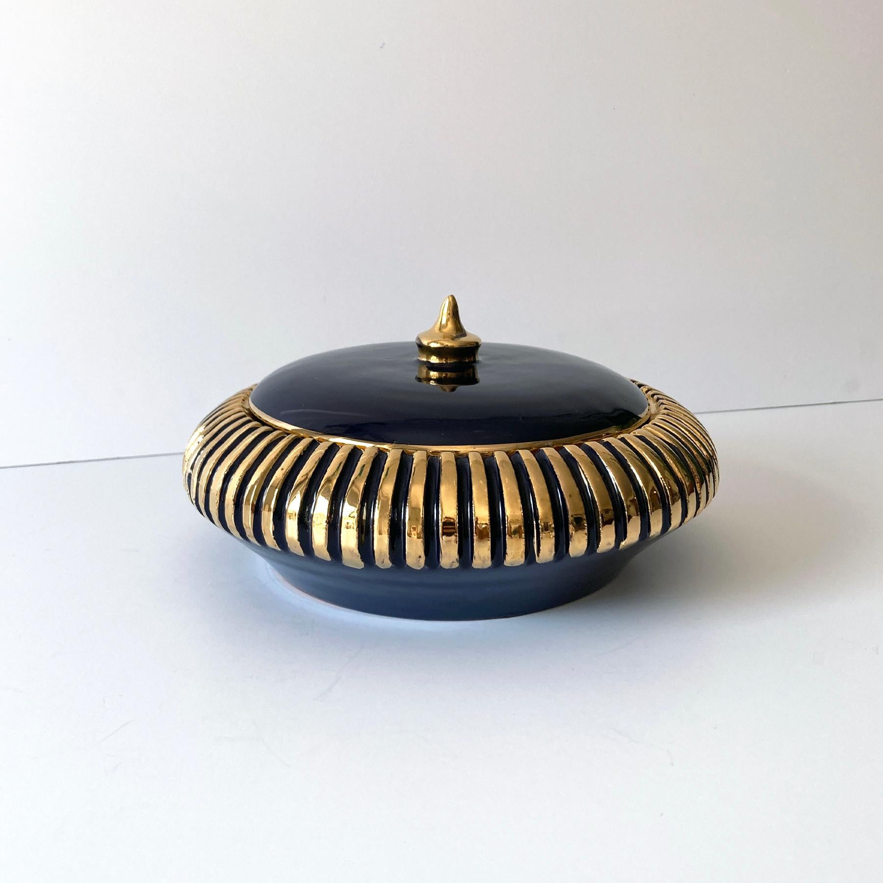 Schöne italienische Dose mit rundem Deckel in Marineblau und Gold. Der dunkelblaue Schirm steht in schönem Kontrast zu den goldenen, gerippten Akzenten an den Seiten und auf dem Endstück. Die Größe macht dieses Stück vielseitig einsetzbar, als