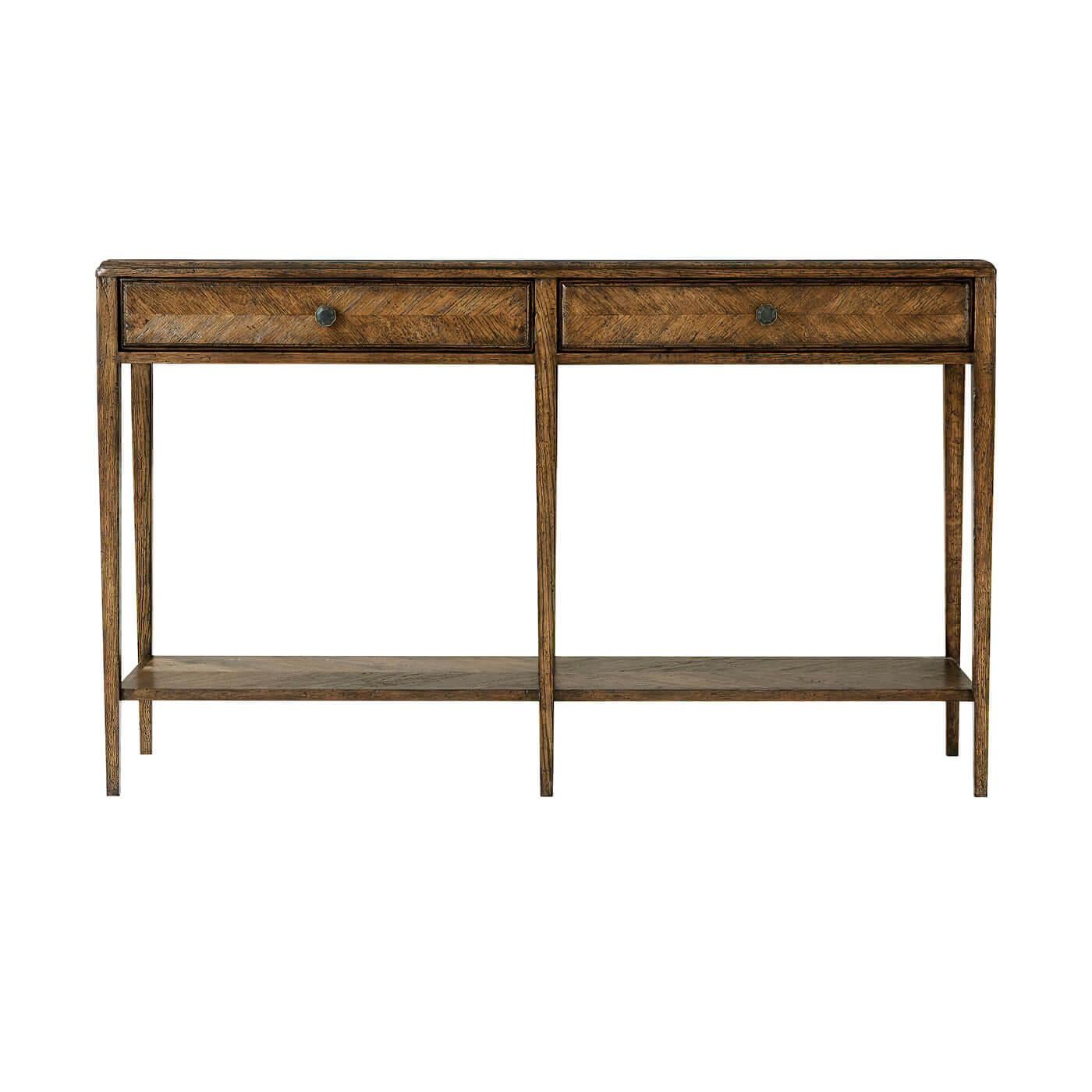 An Italian neo-classic style oak parquetry two-drawer console table accentuated with tapered legs. This beautiful two-tiered herringbone console table includes a rectangular oak parquetry top and two frieze drawers accented with Verde Bronze