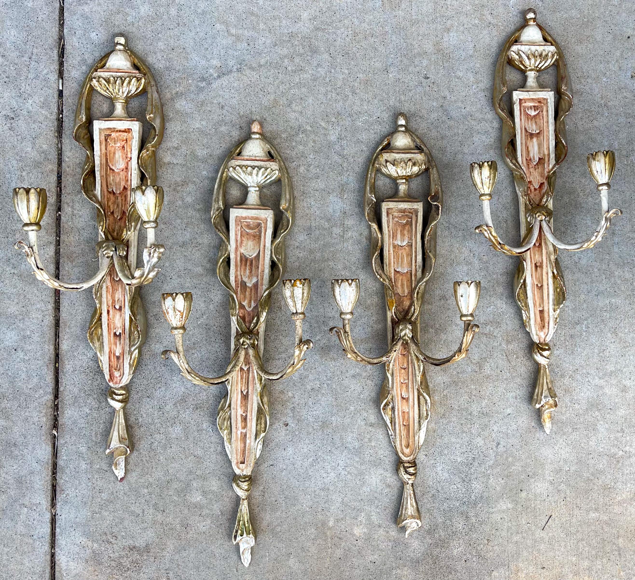 These are wonderful! This is a set of four neo-classical style silver giltwood and painted sconces. Note the urn form with faux drapes cascading down each side. The cream and salmon tones give a soothing elegance to the set. They are not electrified