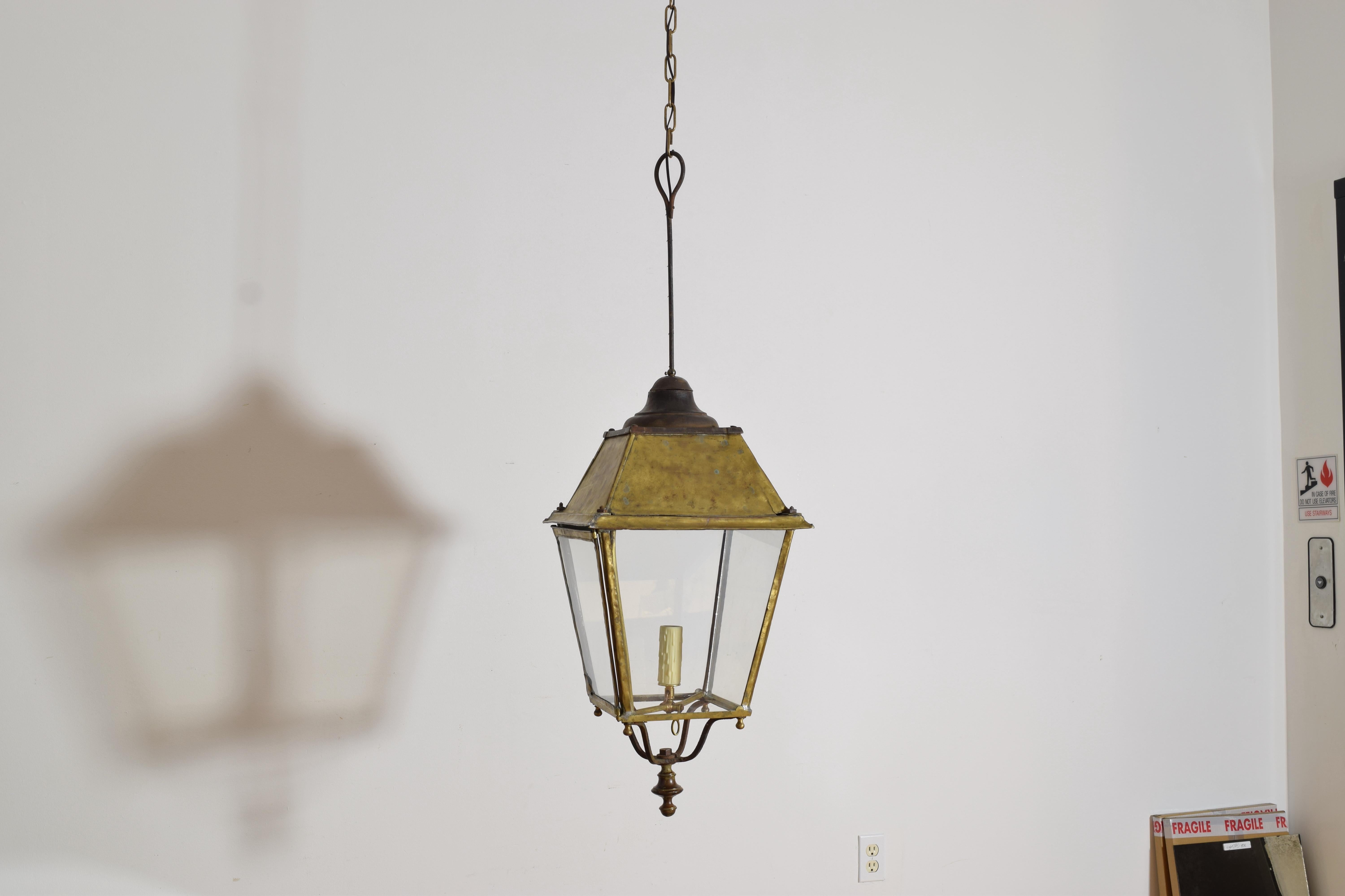 the lantern, now electrified, formerly a gas lantern hangs from an iron post and has a 4-sided roof and a tapering body with four glass panels, the bottom in iron with a brass terminal, the lantern electrified with a single socket